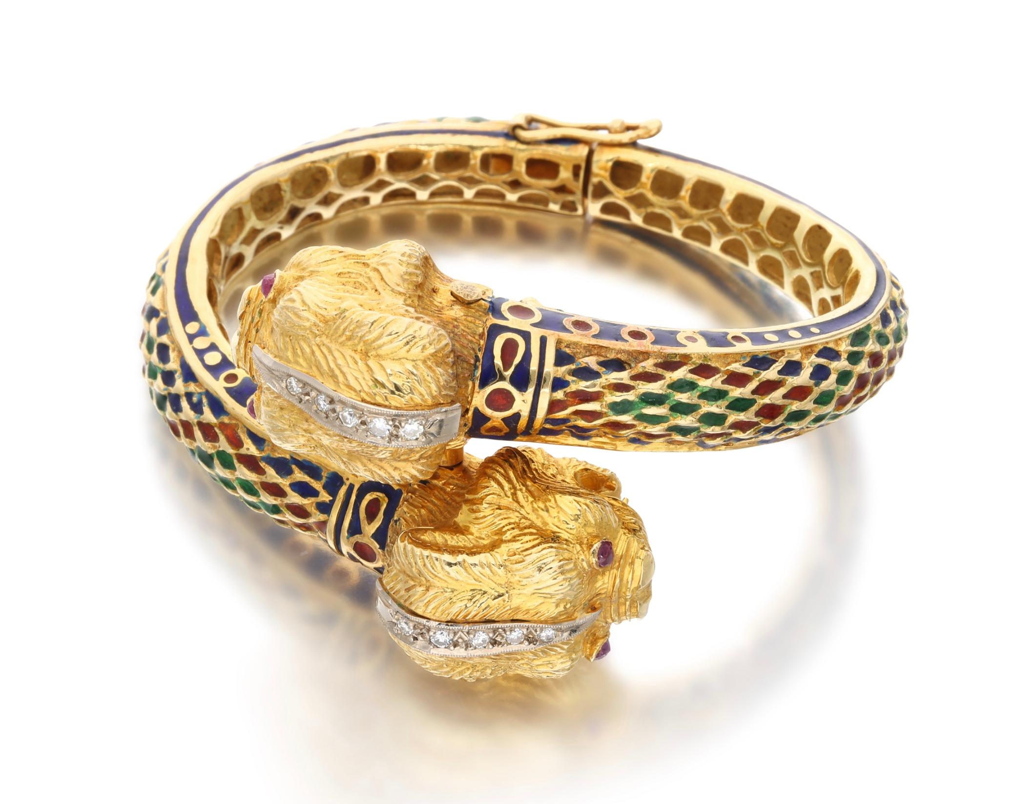 An 18 karat yellow gold bangle bracelet, featuring a two-headed chimera that has eyes made out of rubies. The chimera's head is lined with round-cut diamonds weighing a total of approximately 0.20 carat. Its body is accented by enamel. Made in