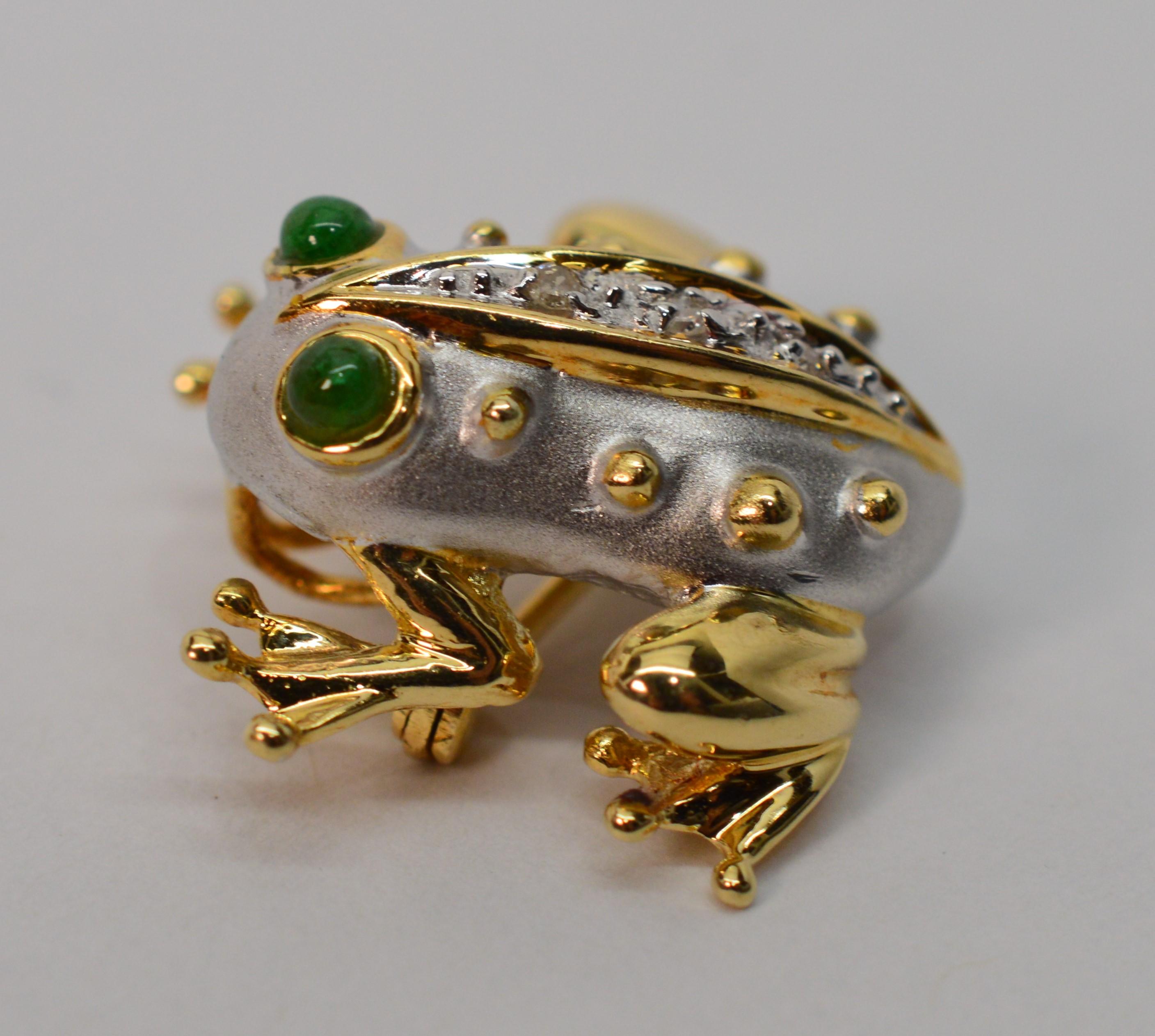 This adorable amphibian looks poised to take his next leap. Made of fourteen karat 14k yellow gold with hand painted rhodium accents, emerald cabochons serve as eyes and faceted diamond accents enhance his back. The piece is fitted with a bail to be