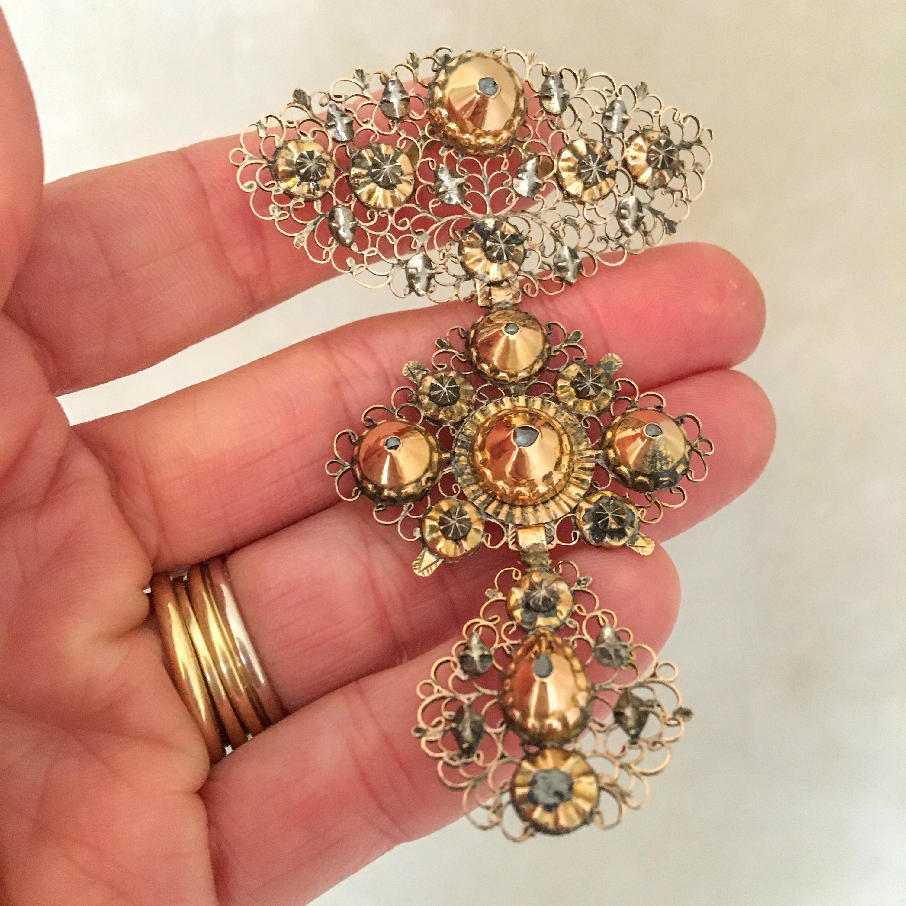 This is an antique 18th century triple pendant crafted in rose gold with touches of silver. A pendant of three graduated panels of open scrollwork and domes set with diamonds. An estate jewel - encrusted with six individual small diamonds within a
