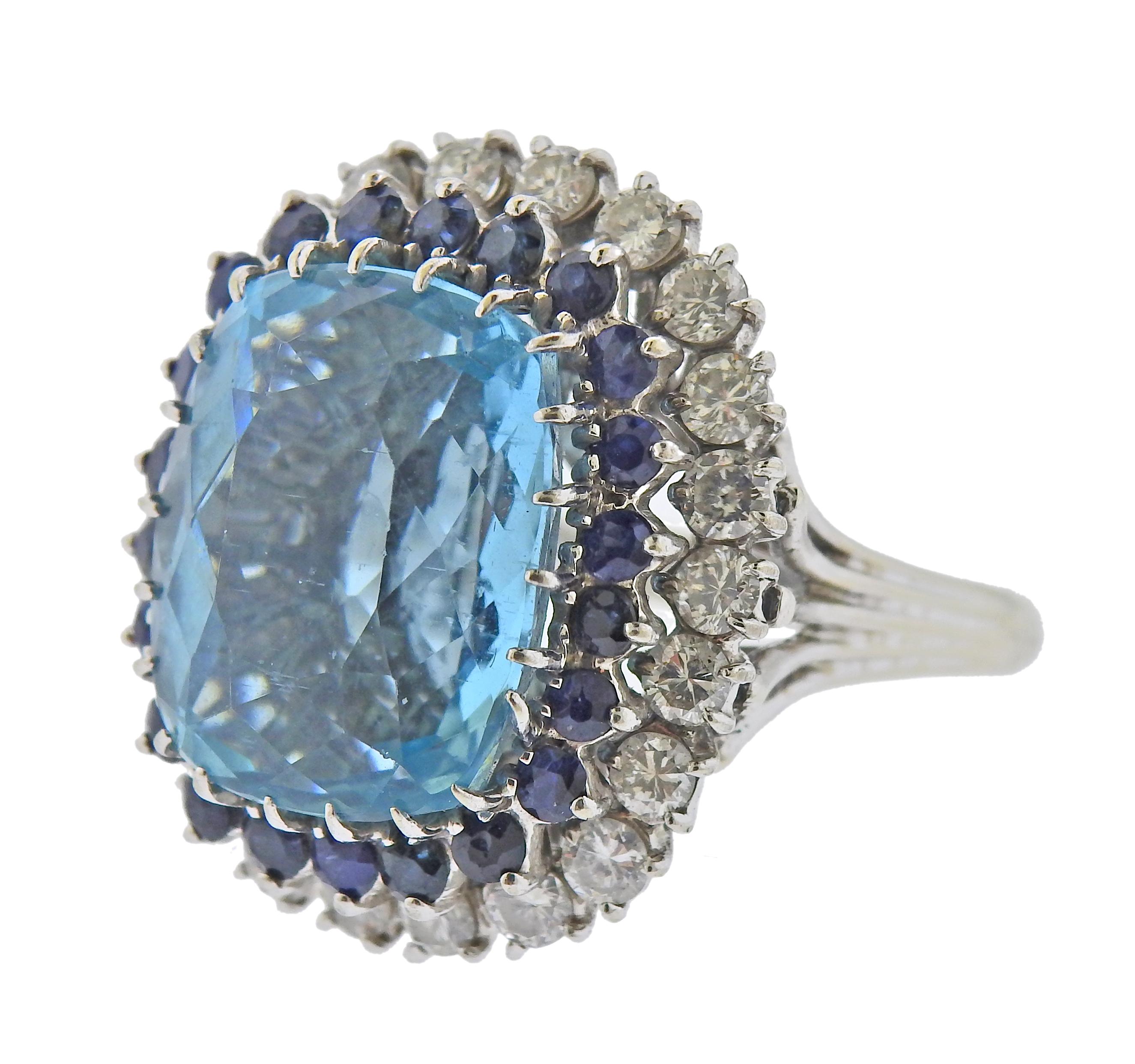 Large 18k gold ring, with center approx. 14.5ct aquamarine (approx. 17.2 x 14.5 x 9.5mm) , surrounded with sapphires and approx. 2.20ctw in diamonds. Ring size - 9.75, ring top - 26mm x 24mm. Tested 18k. Weight - 14.5 grams.