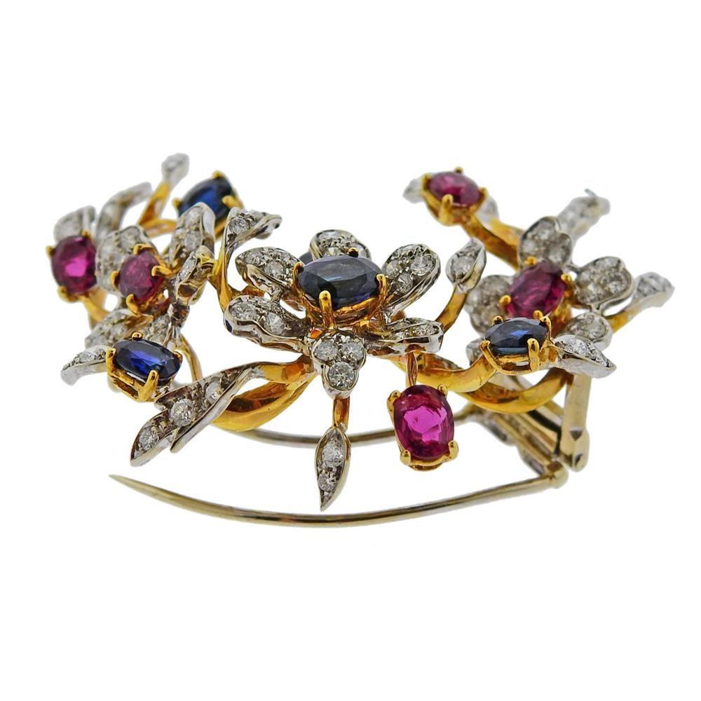 18k white and yellow gold brooch, set with oval blue sapphires and rubies, surrounded with approx. 1.30-1.40ctw in diamonds. Brooch measures 55mm x 55mm. Tested 18k. Weight-  21.2 grams.