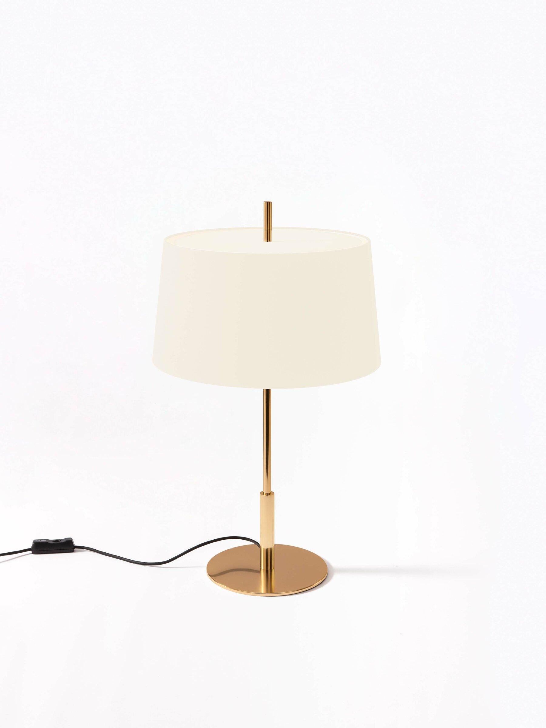 Gold Diana table lamp by Federico Correa, Alfonso Milá, Miguel Milá
Dimensions: D 45 x H 78 cm.
Materials: white linen, metal.
Available in black or white lampshade and in gold or nickel finish.

In keeping with the calling of its creators, the