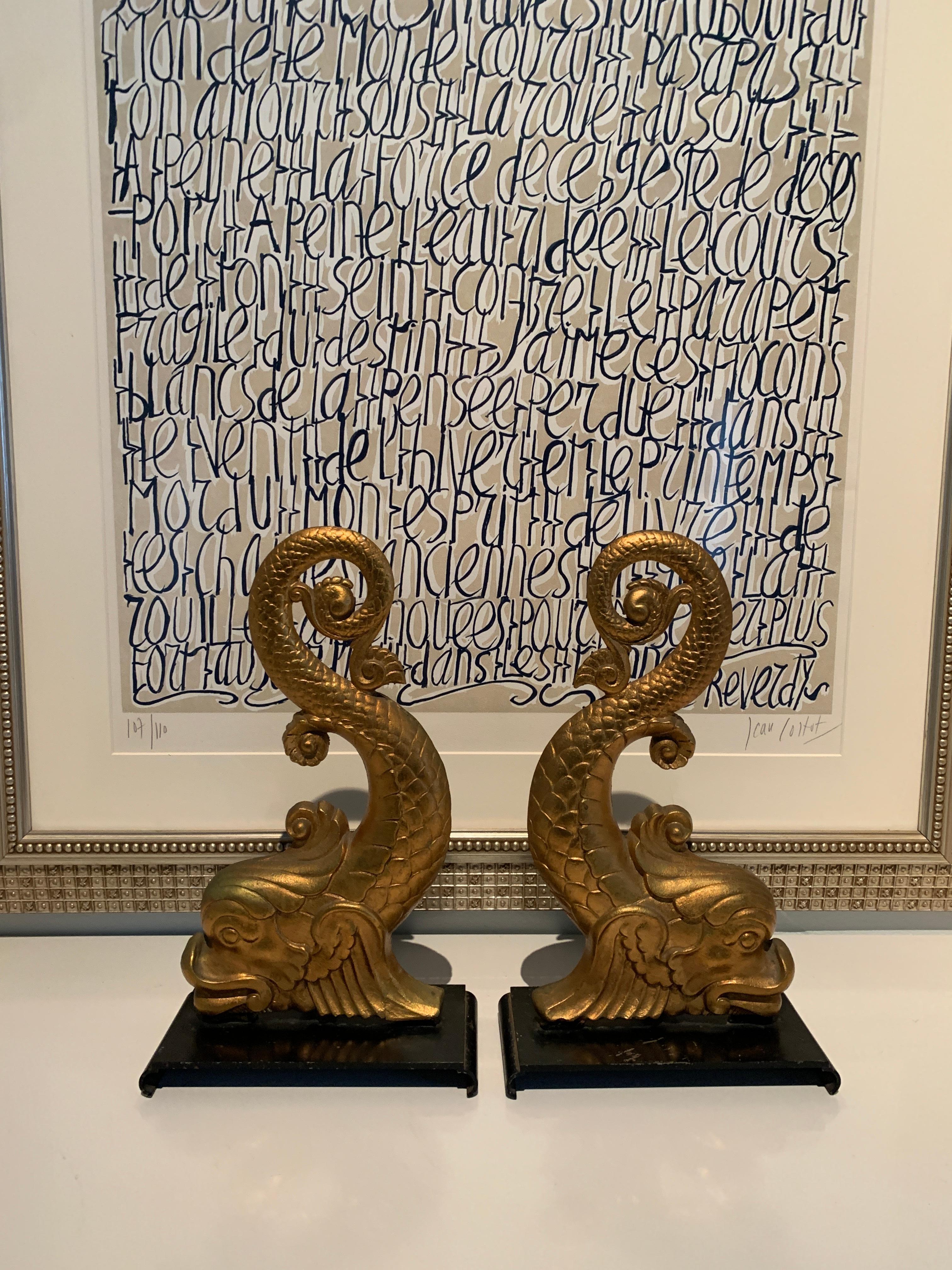 A pair of gilt dolphin andirons or bookends. The pieces are spectacular to look at and are the perfect addition to many fireplaces - while they do not have the rods to hold the logs they are a wonderful pair. They would also make exceptional