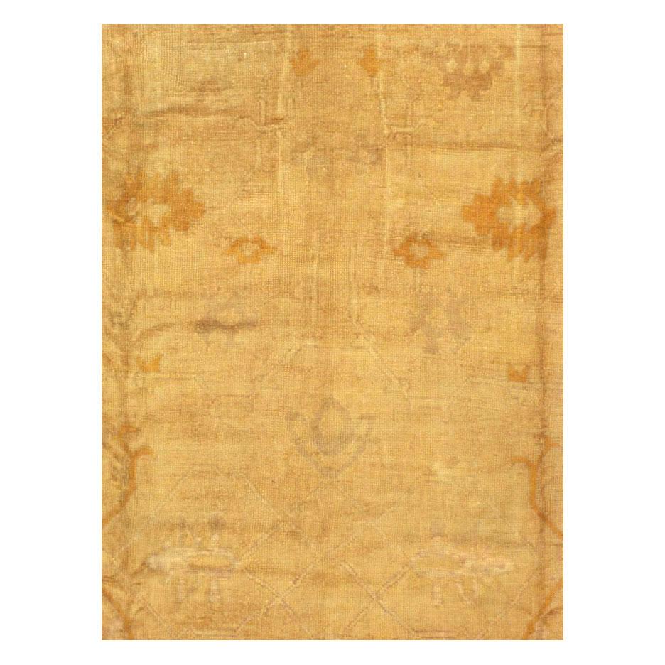 An antique Turkish Oushak large room size carpet in square format handmade during the early 20th century. The tone-on-tone design incorporates a gold background with only light sketching in rust gold to complete the design. The lightly sketched
