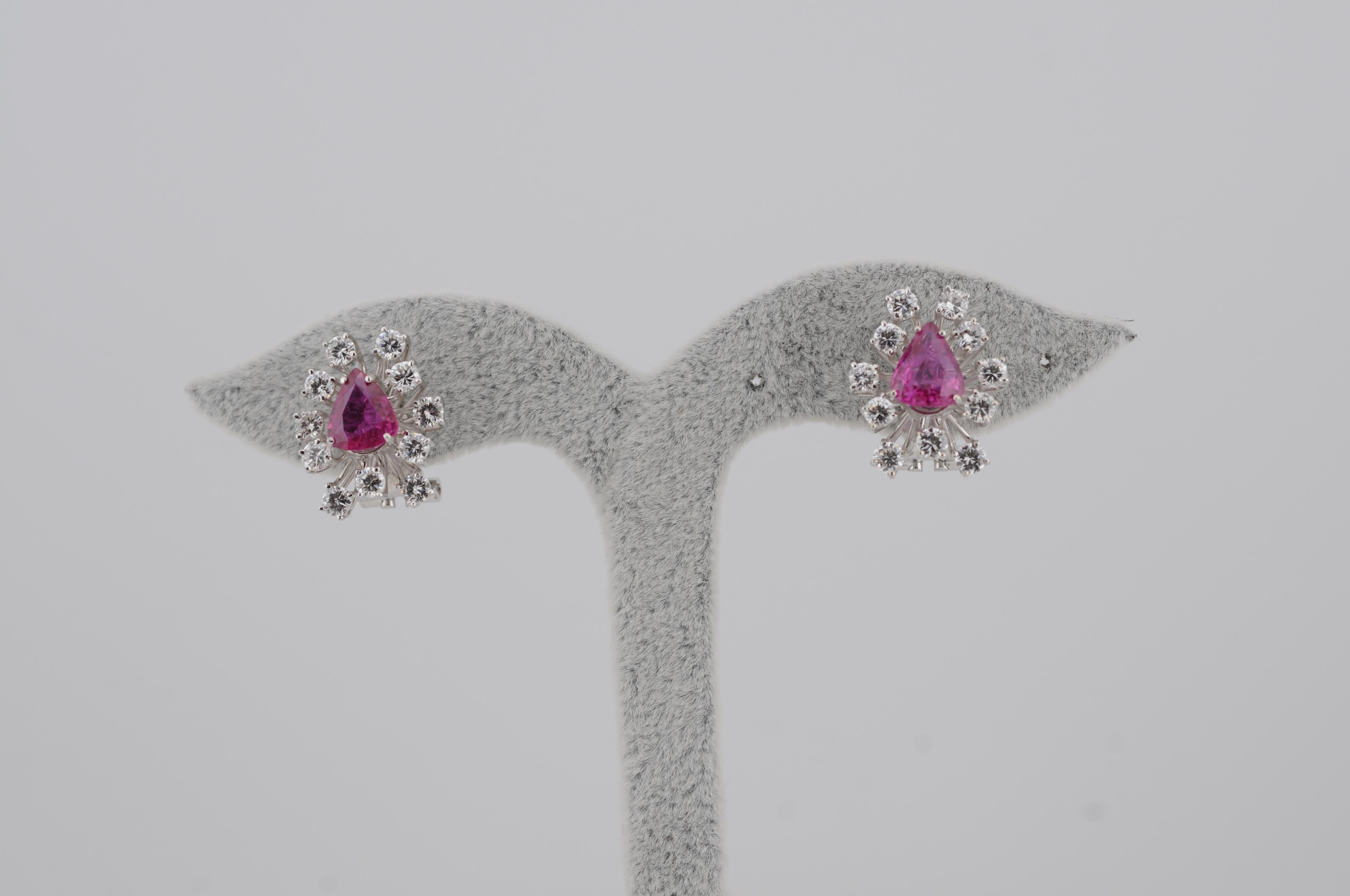 Elegante paio di orecchini in oro bianco 18 carati con due rubini naturali non trattati con taglio a pera di circa 1,2 carati ciascuno (totale 2,4 carati). I rubini sono circondati da 22 diamanti a taglio brillante con un peso totale stimato di