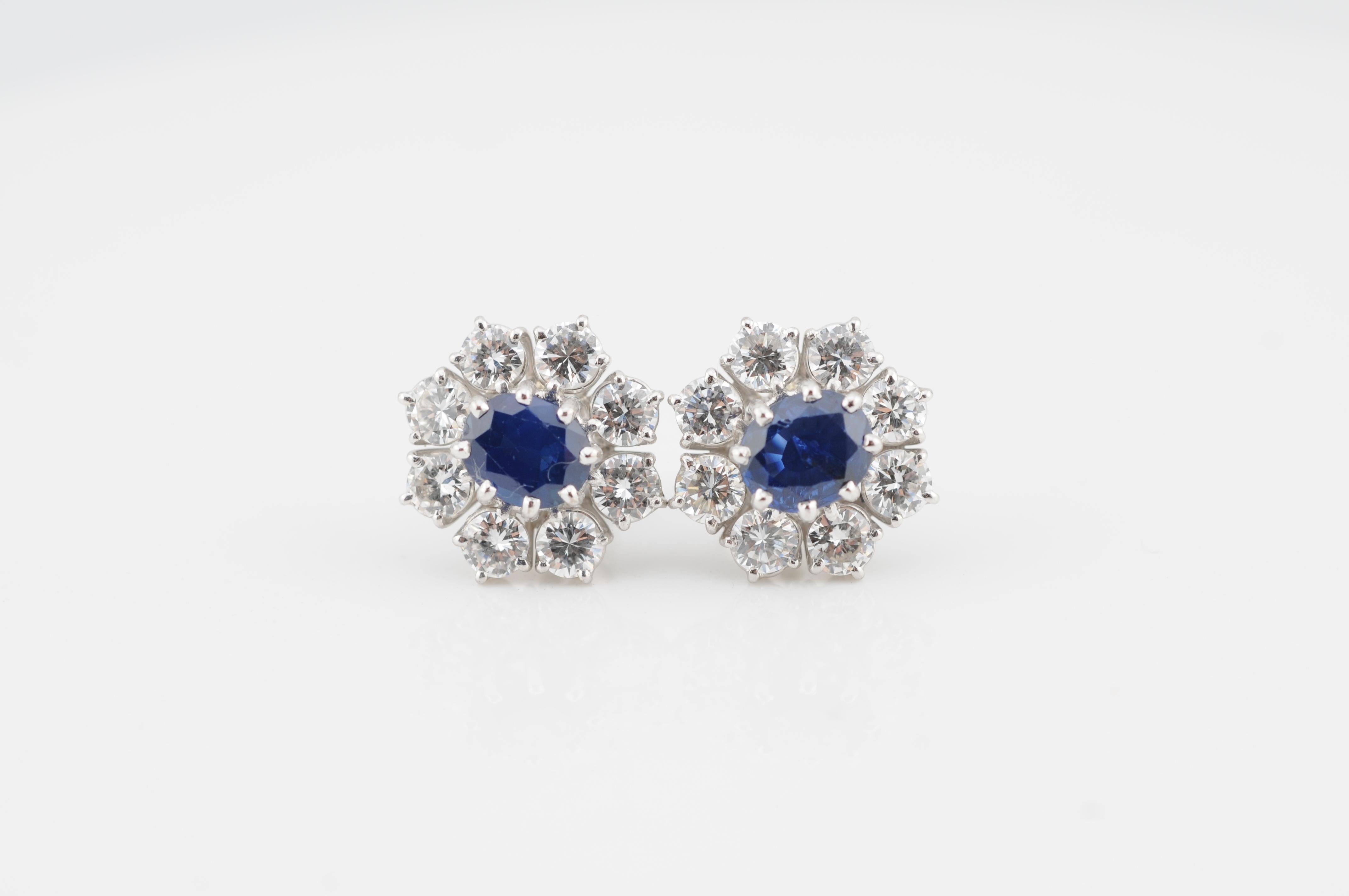 Eleganti orecchini in oro bianco 18 carati con due zaffiri naturali di Ceylon di circa 1,50 carati ciascuno (totale ~3,00 carati). Ogni zaffiro è incorniciato da 8 diamanti taglio brillante, ciascuno di circa 0,12 carati, per un peso totale di