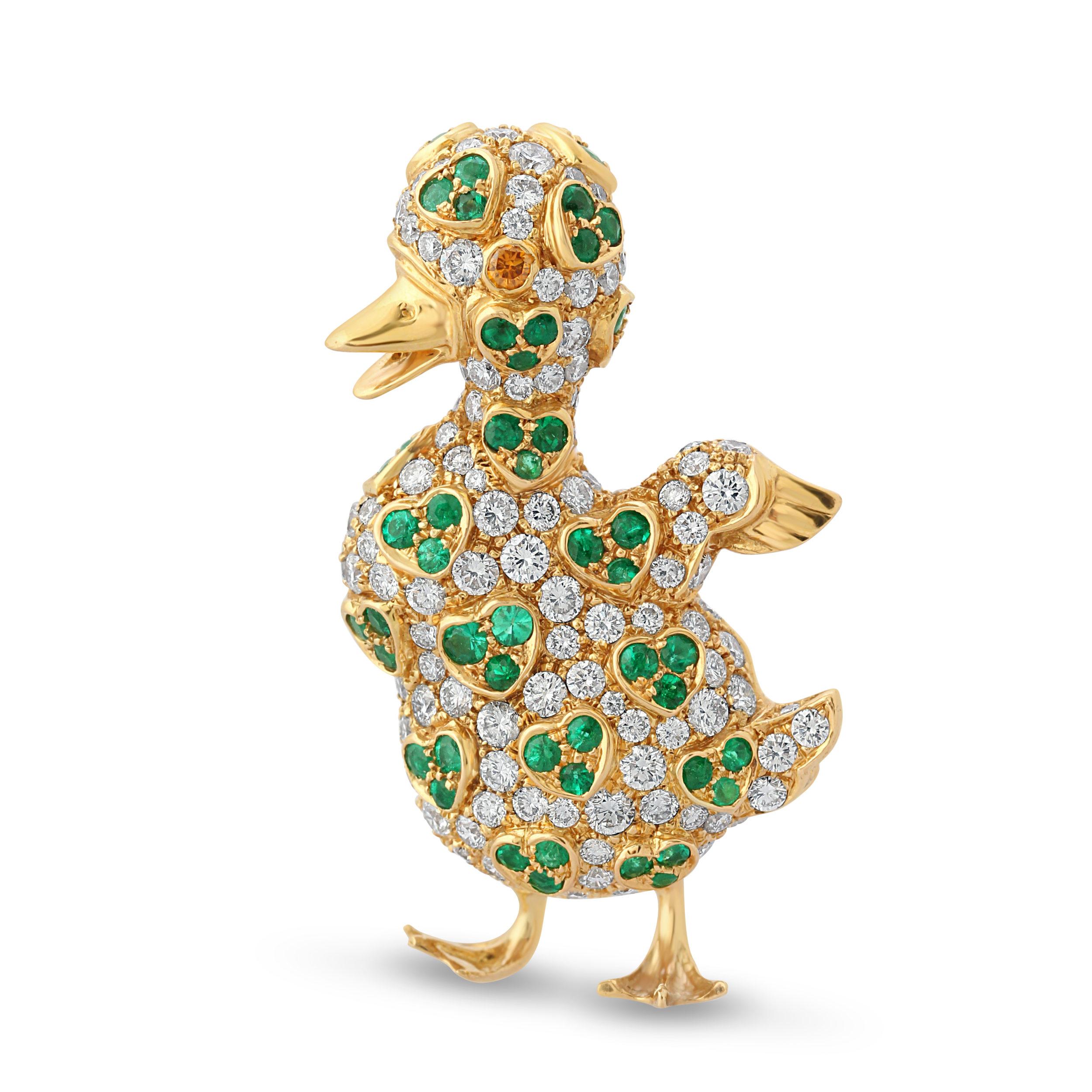 A delightful duck brooch by Reza. Set with 1.11 carats of emeralds in repeating heart motifs surrounded by round brilliant-cut diamonds with a fancy yellow diamond eye. Total diamond weight = 2.59 carats.
