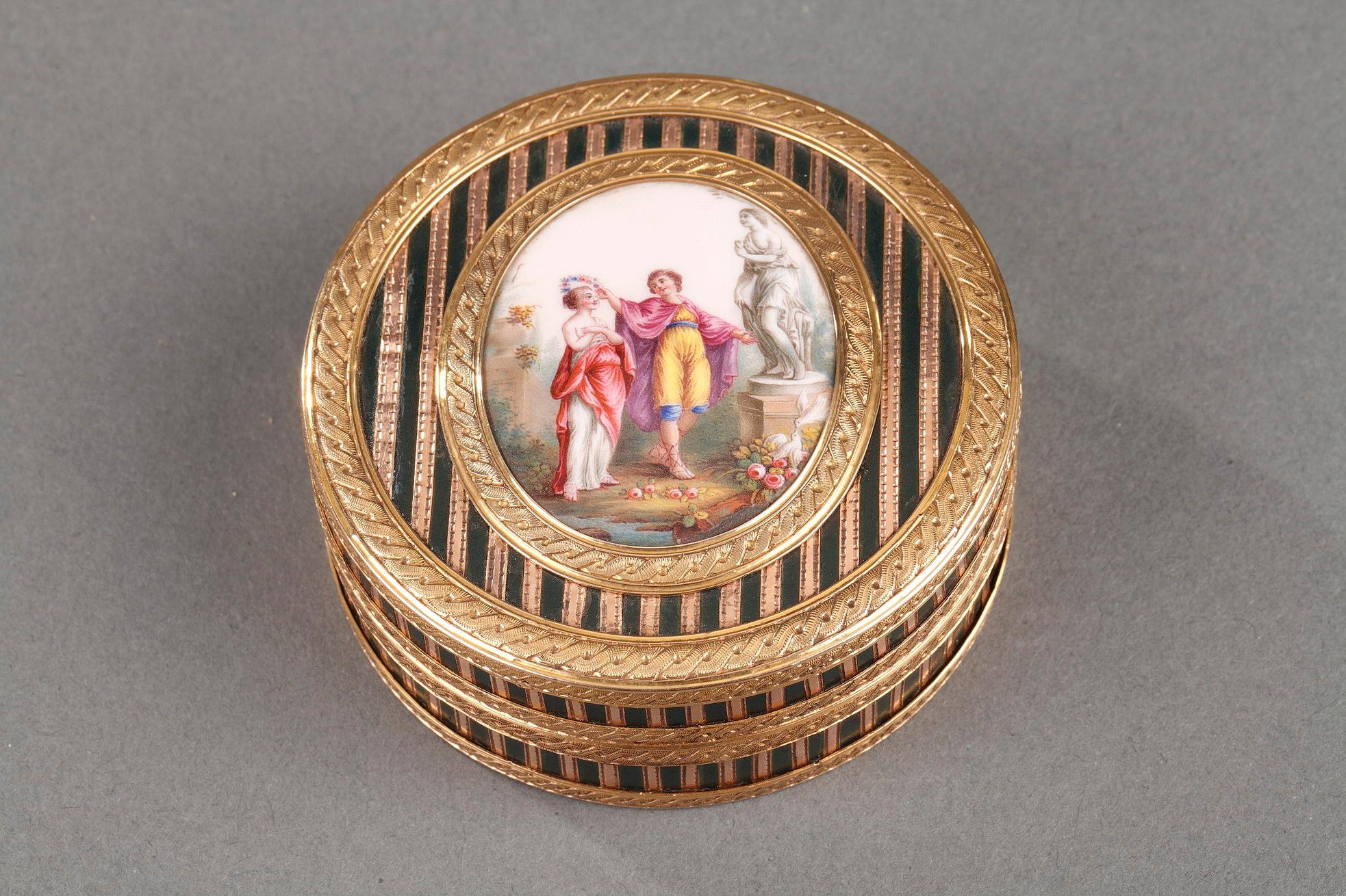 Circular box in several shades of gold, enamel, and composite materials. The box features varnish (lacquer) inlaid with thin bands of pink gold. A yellow gold mounting embellished with an interlaced motif frames the box and a central, oval