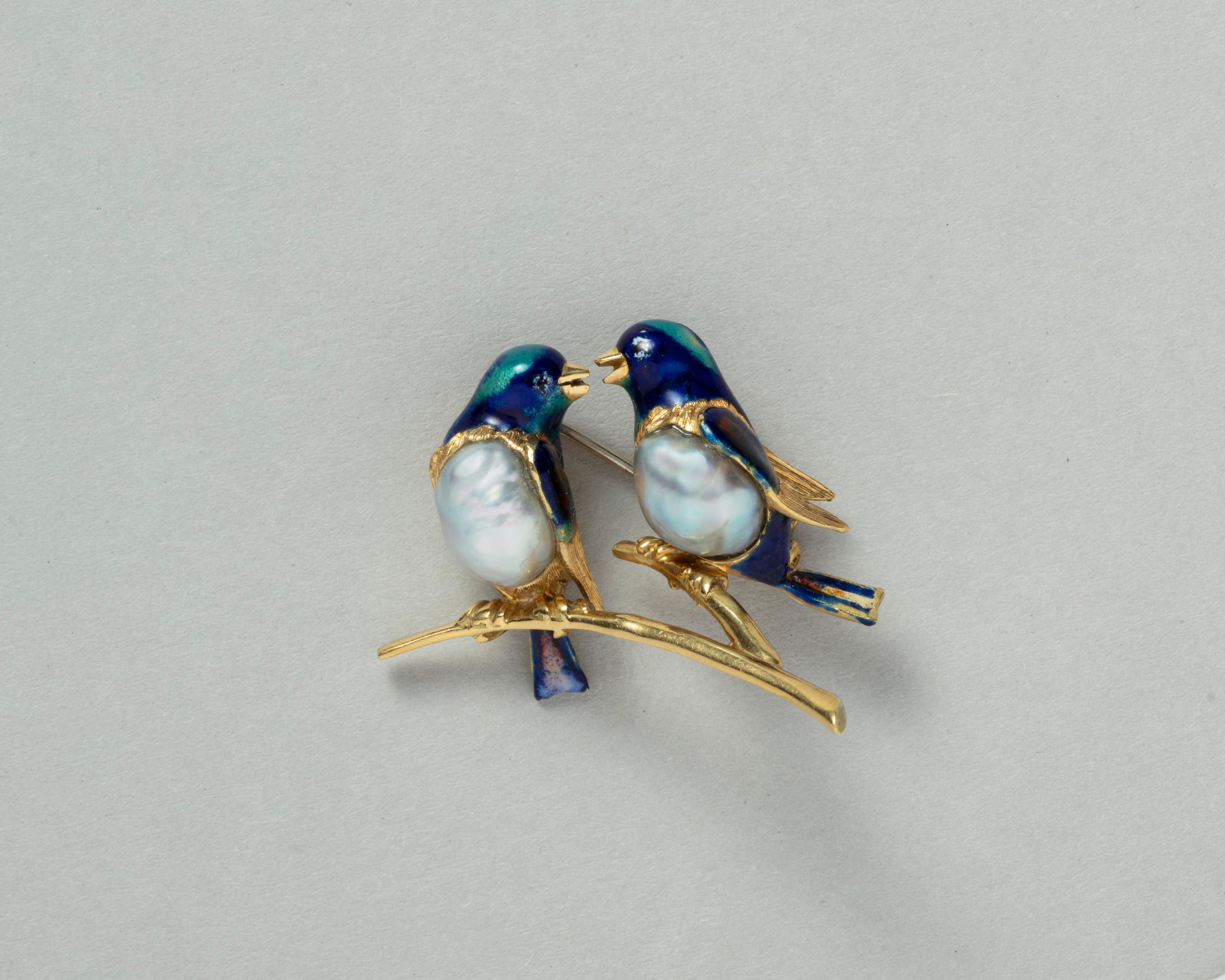 An 18 carat gold brooch with two birds on a branch, they have colorful enamel and a large unpierced grey pearl as their belly, Italian, circa 1970s.

weight: 13.41 gram
dimension: 4 x 2.5 cm

