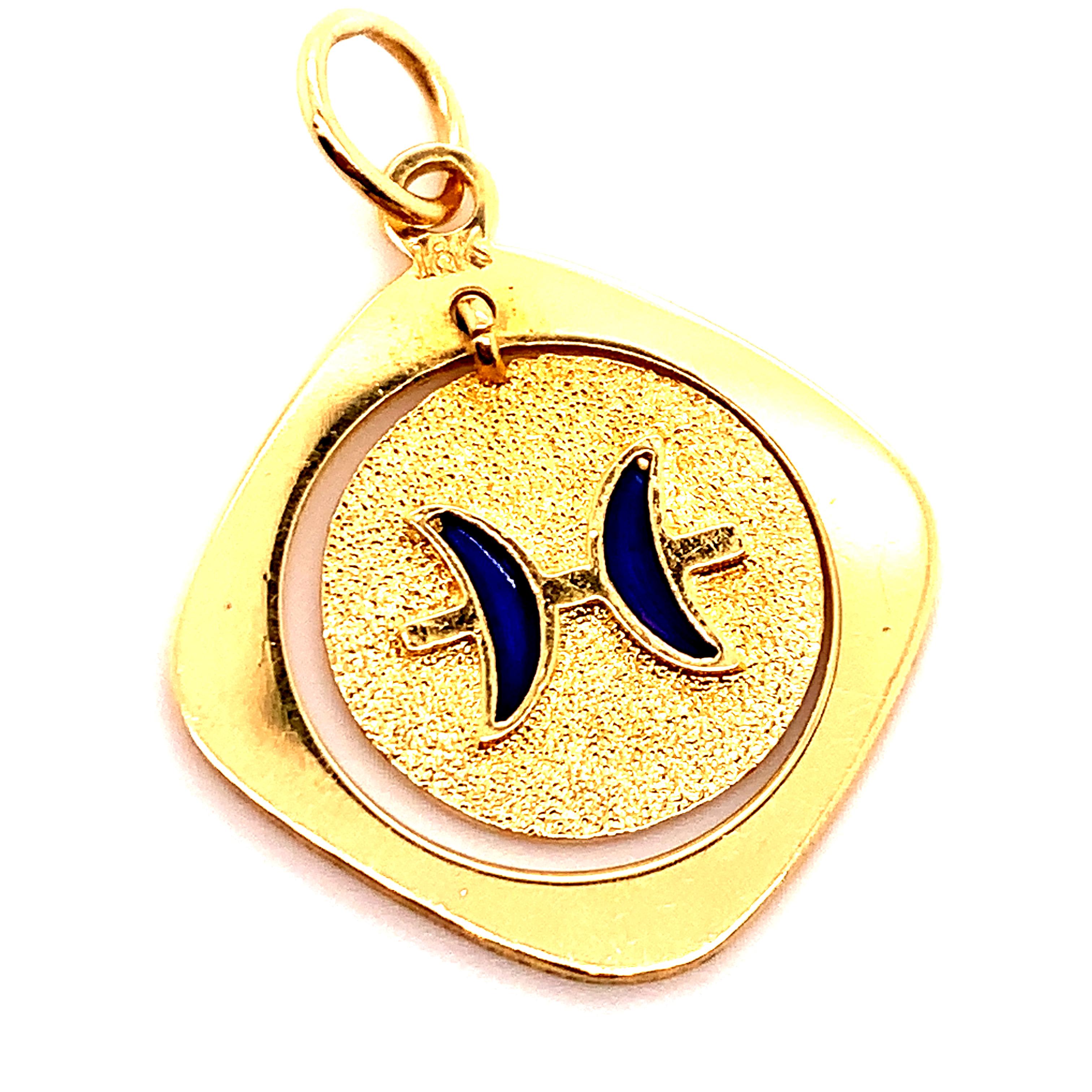 Charming charm: a round charm with two blue enamel fish on the front and a blue enamel PISCES symbol on the back.  The charm is suspended within  a softly curved diamond-shaped setting.  The round charm, 18K textured gold,  is moveable. The outer