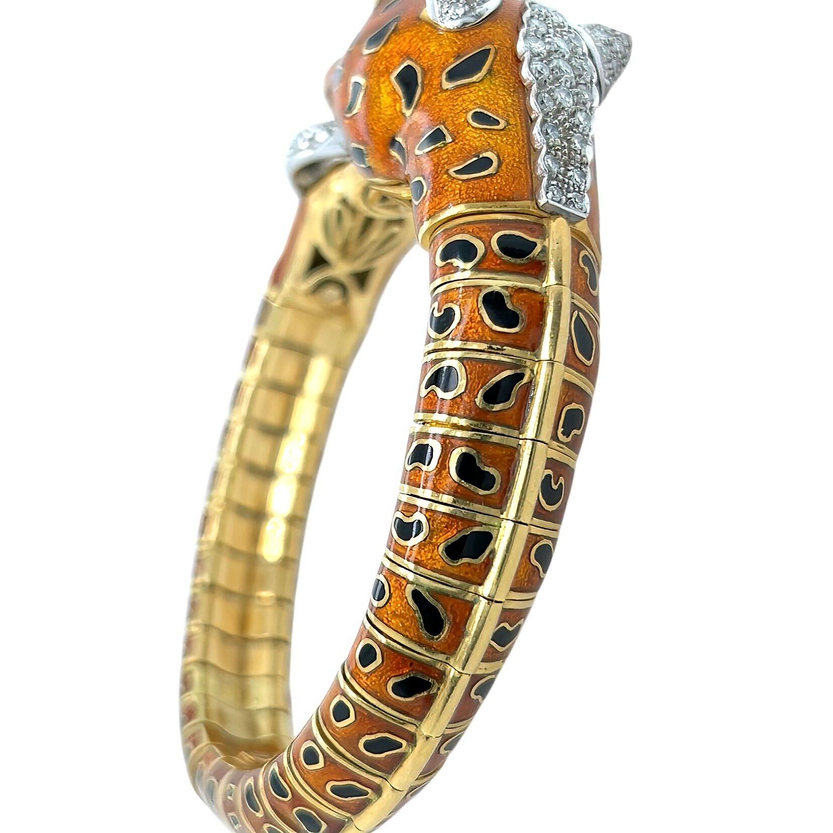 An 18 karat yellow and white gold, enamel, ruby and diamond bracelet.  The yellow gold bracelet designed as the head of a leopard in deep orange enamel with black enamel rosettes and two pear shaped rubies for eyes, the leopard's ears enhanced with