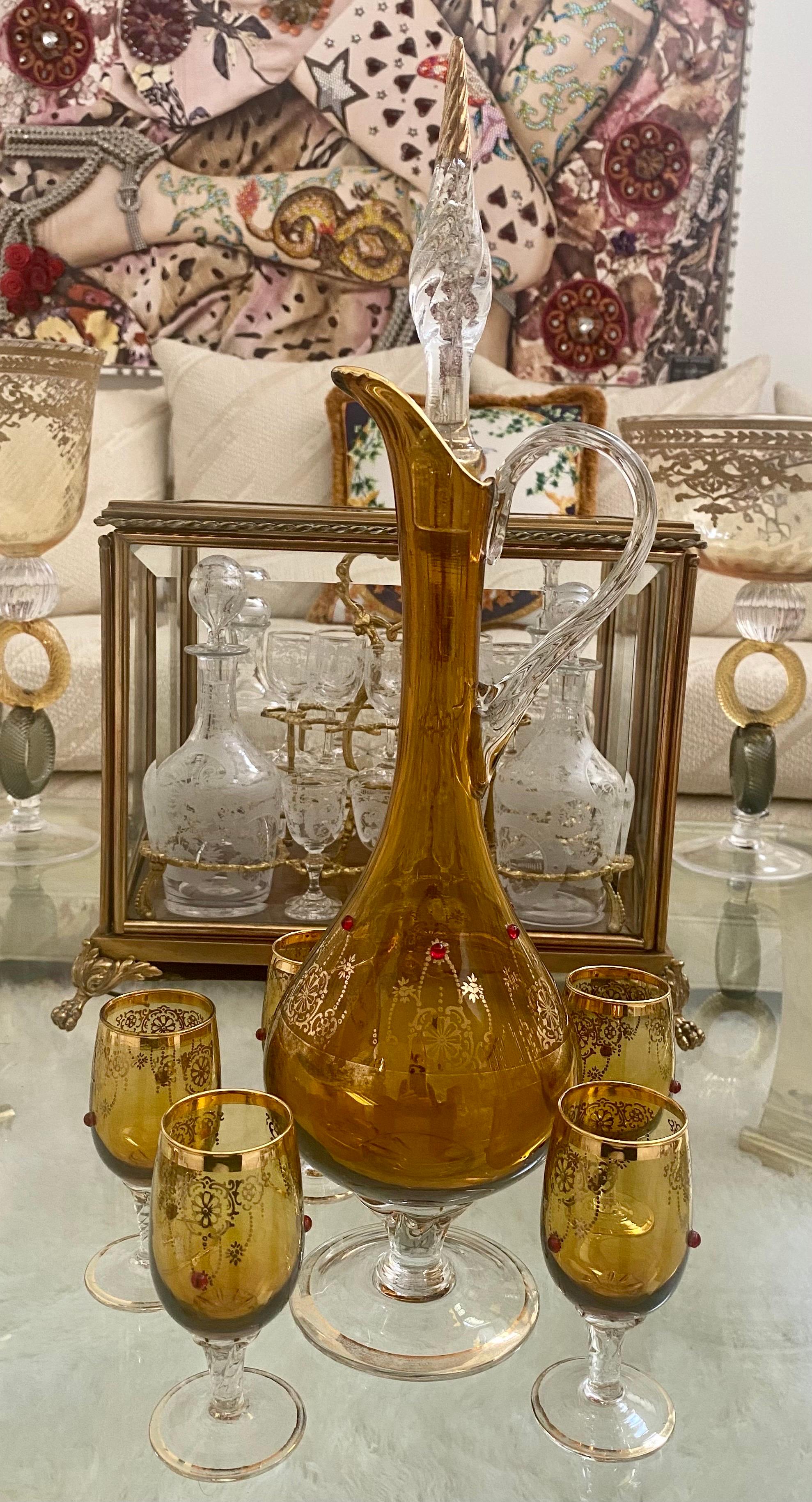 A lovely set of Venetian amber and clear glass consisting of a decanter, 17.25 inches tall, and 5 cordial glasses, 3.5 inched tall. The set is trimmed and embellished with gold. Each piece is decorated with red enamel. This set would be a beautiful
