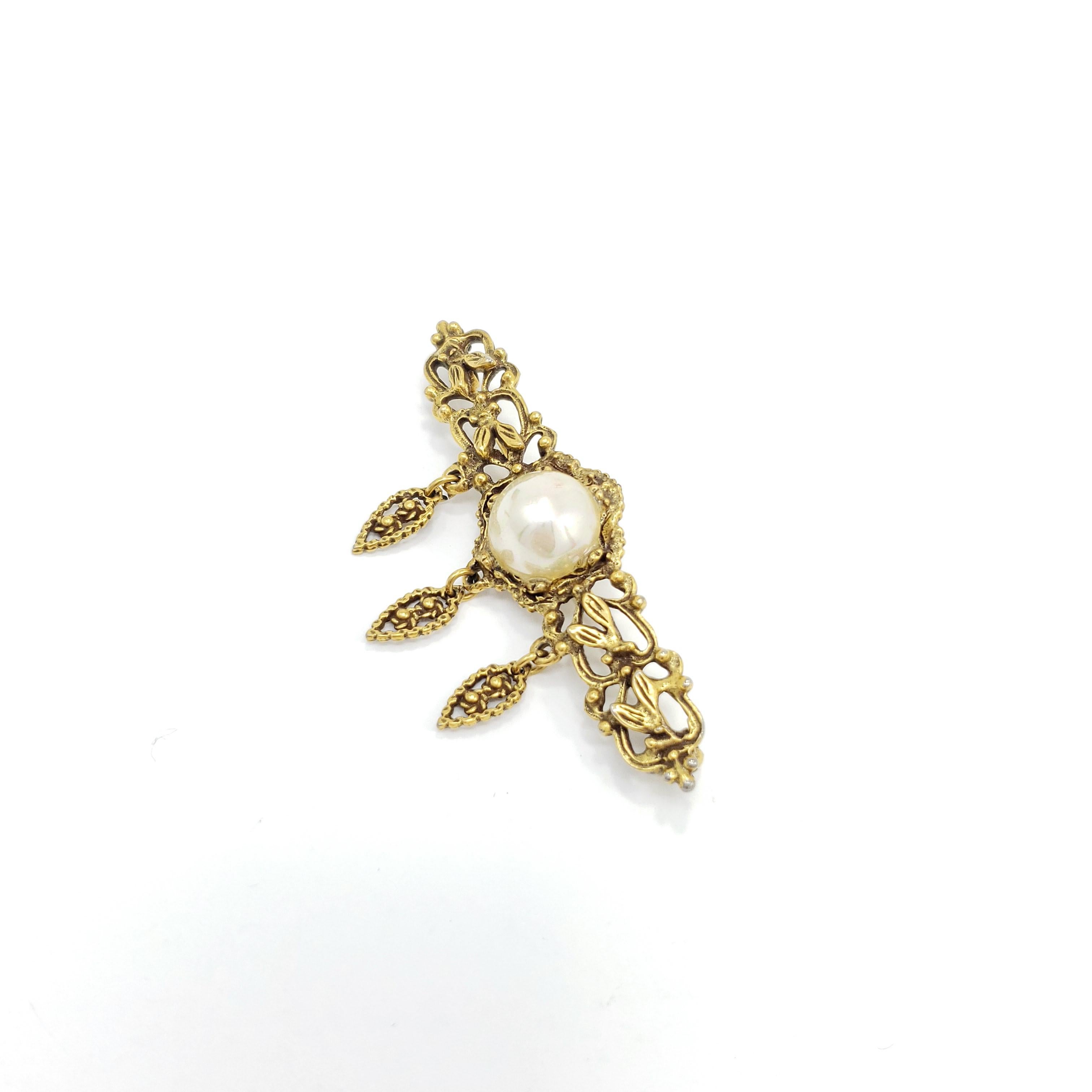 Golden elegance! This mid 1900s, Victorian-style brooch features exquisite floral motifs with a faux pearl centerpiece.

Gold-plated.