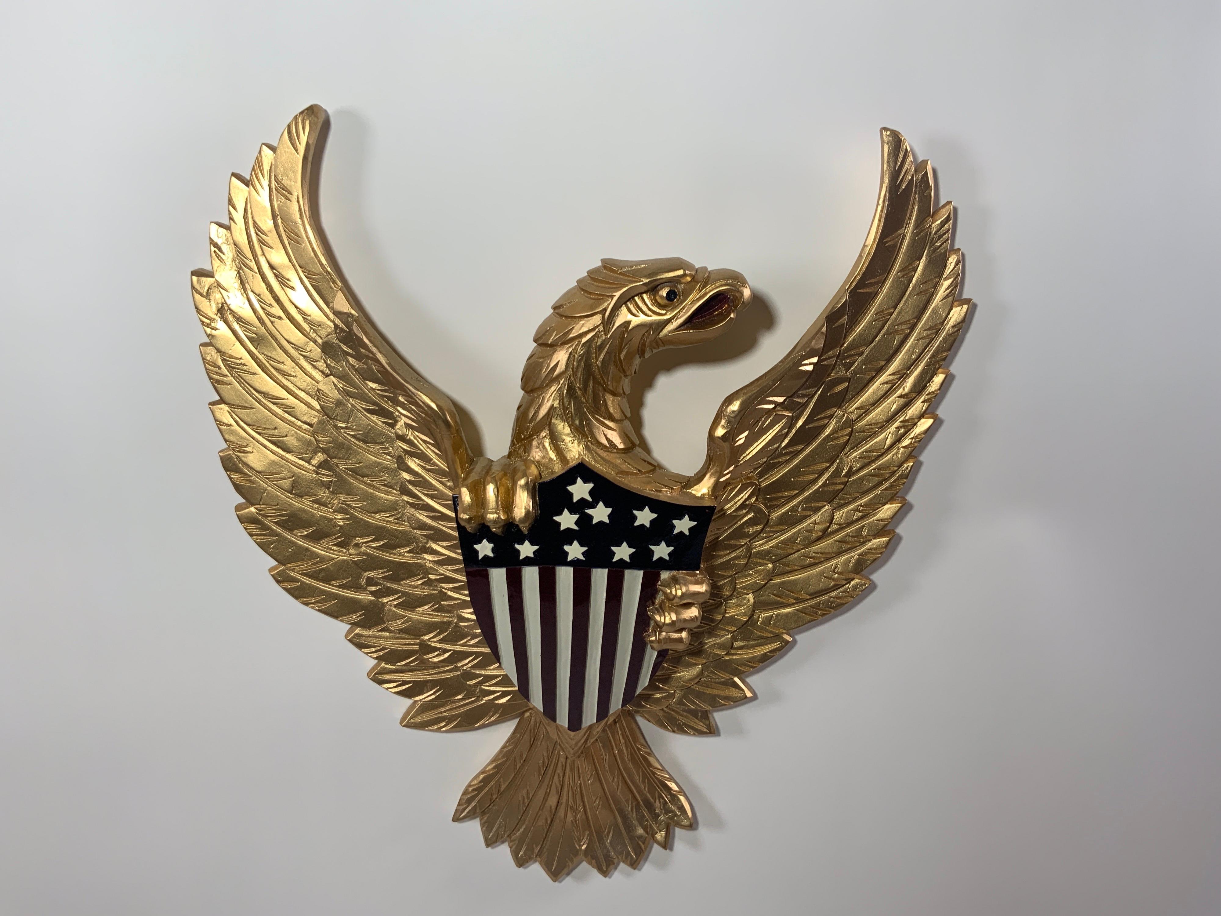 Carved wooden eagle painted in bright gold. Eagle is very detailed and clutching the Great Seal in the likeness of the US Coat of Arms. 

Overall dimensions: 21