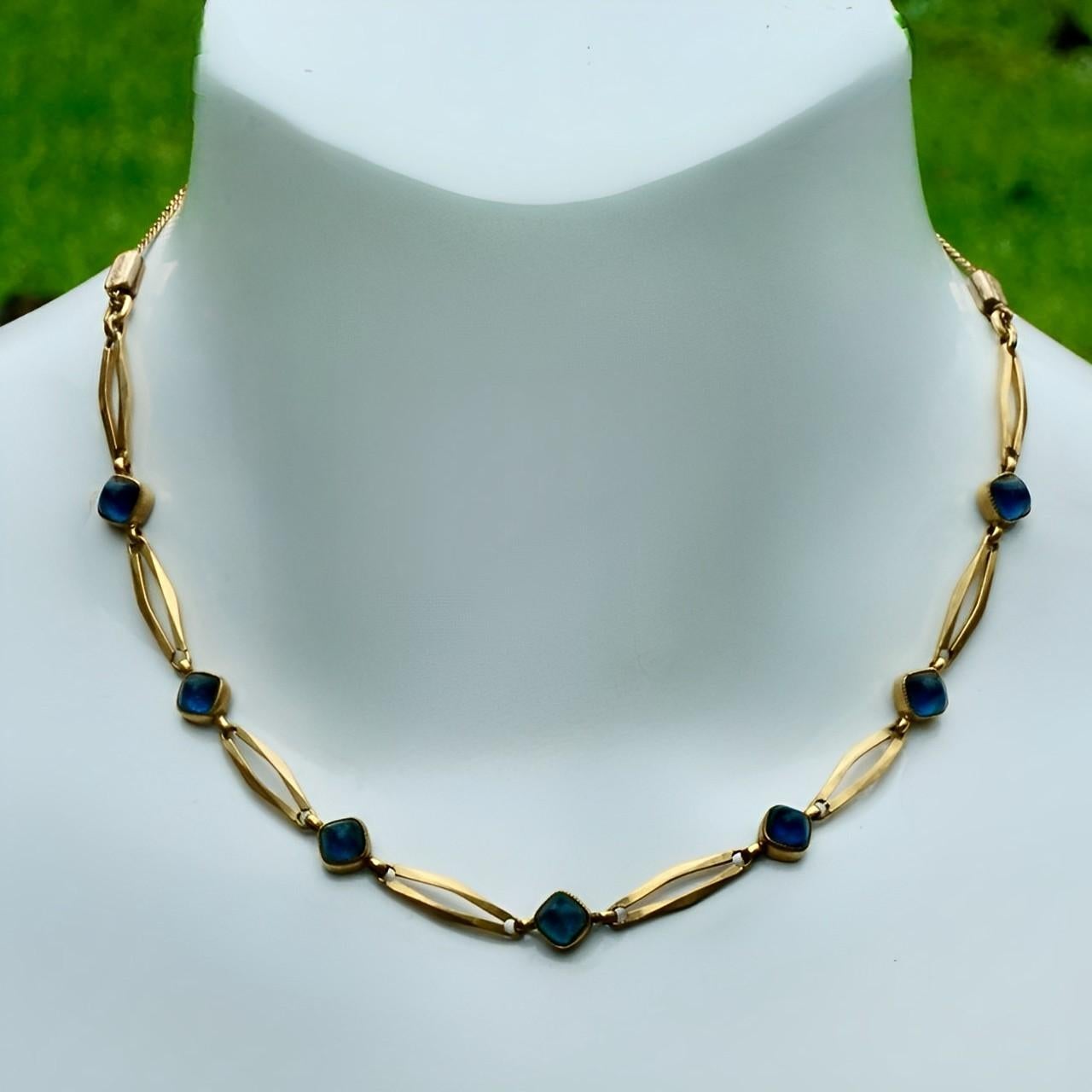 Bellissima collana a maglie in oro con pietre cabochon in vetro blu e due connettori decorati. Le maglie della catena sono saldate. Su uno degli anelli di collegamento c'è un timbro con la dicitura 