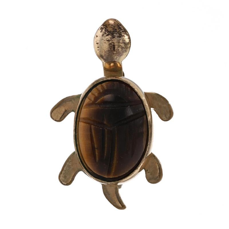Metal Content: 1/20 12k Gold Filled

Stone Information

Natural Tiger Eye
Cut: Scarab carved oval cabochon
Color: Brown & Tan

Style: Brooch
Fastening Type: Hinged Pin and Whale Tail Bullet Clasp
Theme: Turtle, Reptile

Measurements

Tall: 11/16