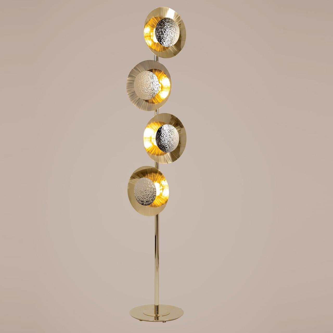  La lampada da terra Gold è caratterizzata da due piastre di ottone arrotondate, disposte con un leggero spazio tra di loro, che permettono a delicate mezzelune di luce di fare capolino. La piastra frontale è martellata a mano con moderne tecniche