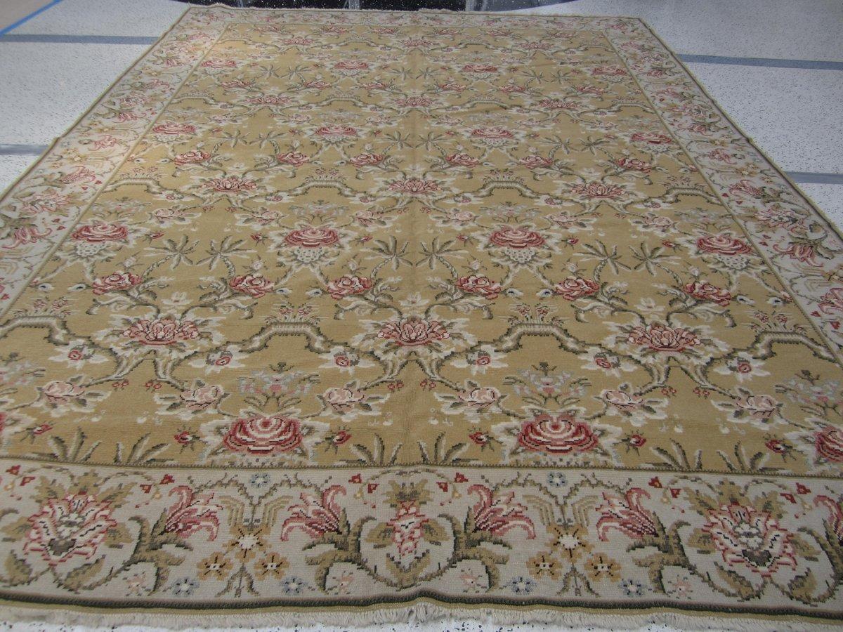 A trellis of pink and red roses against a gold background is the hallmark of this charming and graceful wool area rug. A beige border of colorful blossoms surrounds. Hand knotted.