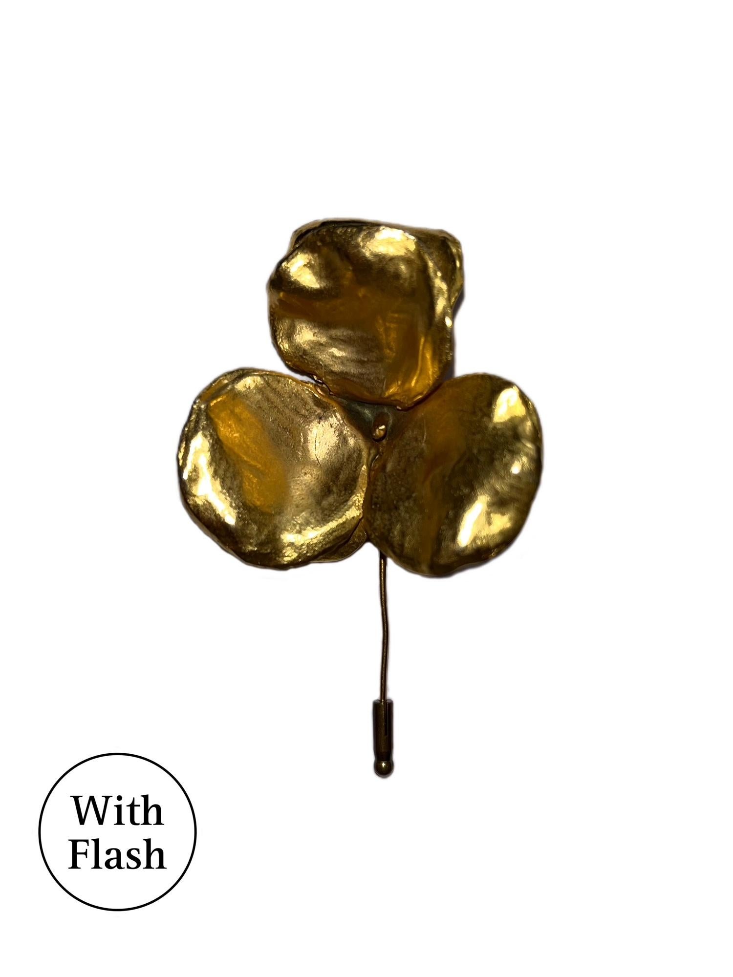 This is an elegant gold-tone brooch with a nature-inspired design, resembling a three-petal flower. The three petals are hammered and irregular, giving them a hand-crafted, organic texture. Its minimalist yet bold design is from the French House