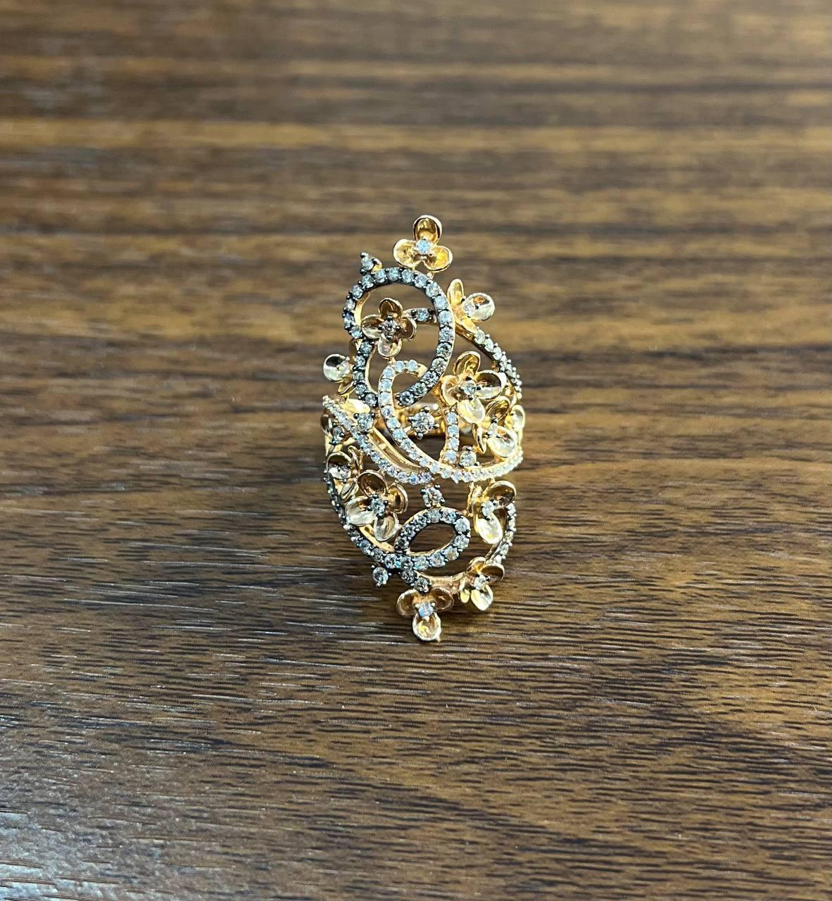 This exquisite piece, designed in gold, features a captivating array of white diamonds that shimmer with every movement. The ring's elaborate design showcases delicate floral motifs intertwined with swirling patterns, creating a harmonious blend of