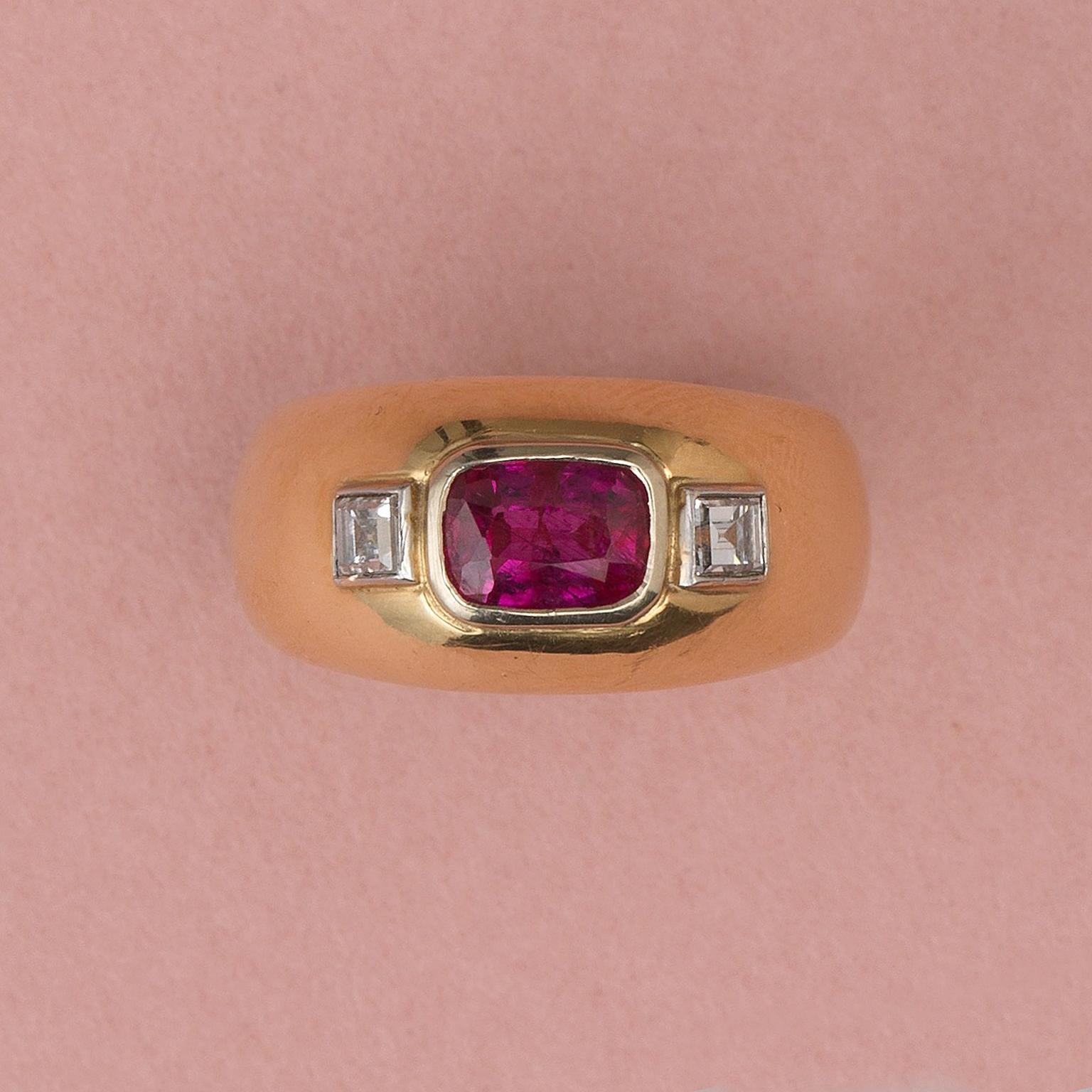 A beautiful, solid 18 carat yellow gold ring flush and vertically set with a table cut strong purplish-red ruby (unheated circa 1.68 carat Thailand origin) on each side is a carré cut diamond in a white gold mounting (circa 0.28 carat total),