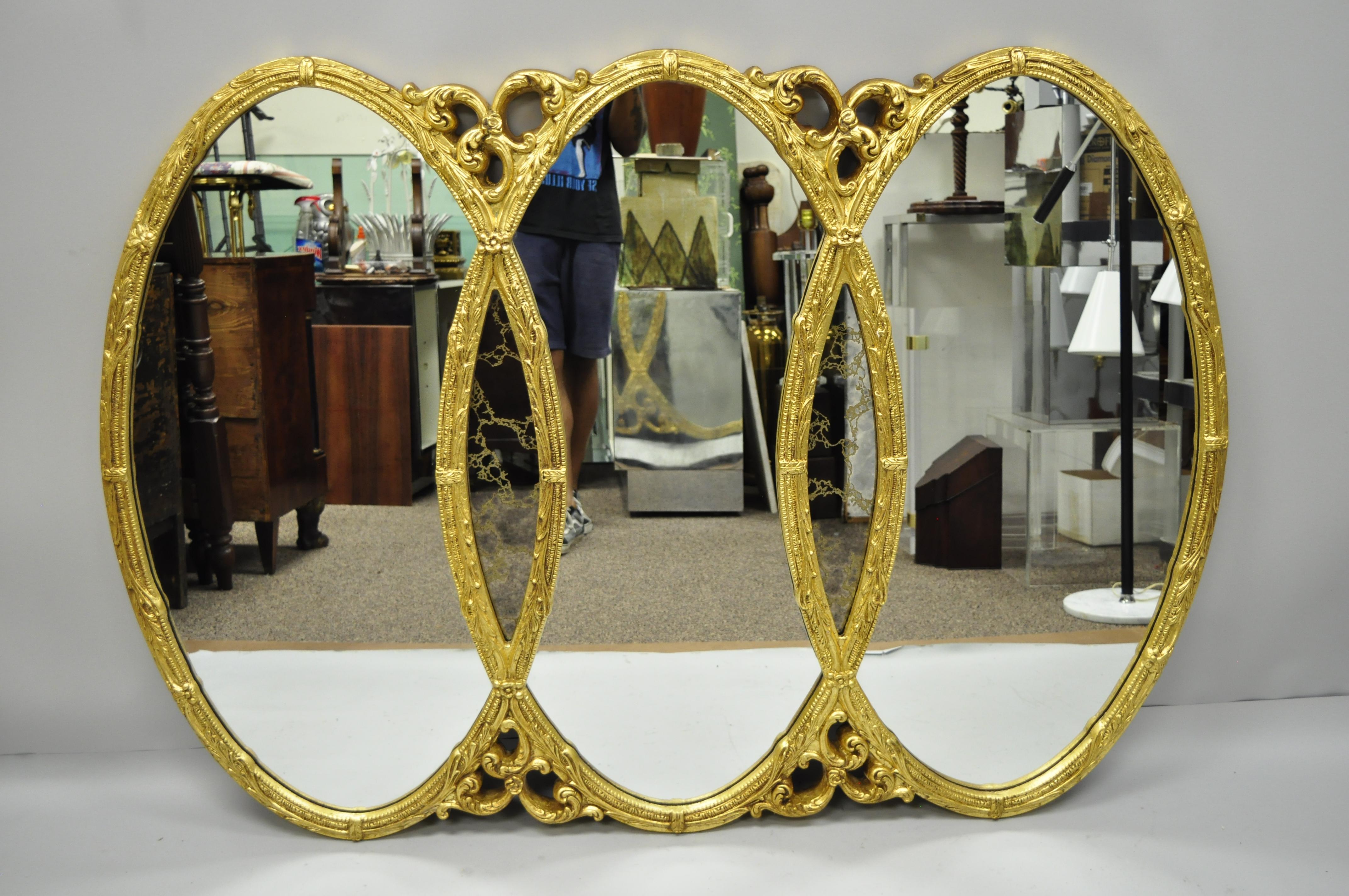 Vintage gold French Hollywood Regency triptych triple interlocking oval wall mirror. Item features gold gilt finish, molded foam frame, Églomisé glass inserts, and great style and form, circa 1960s. Measurements: 45.5