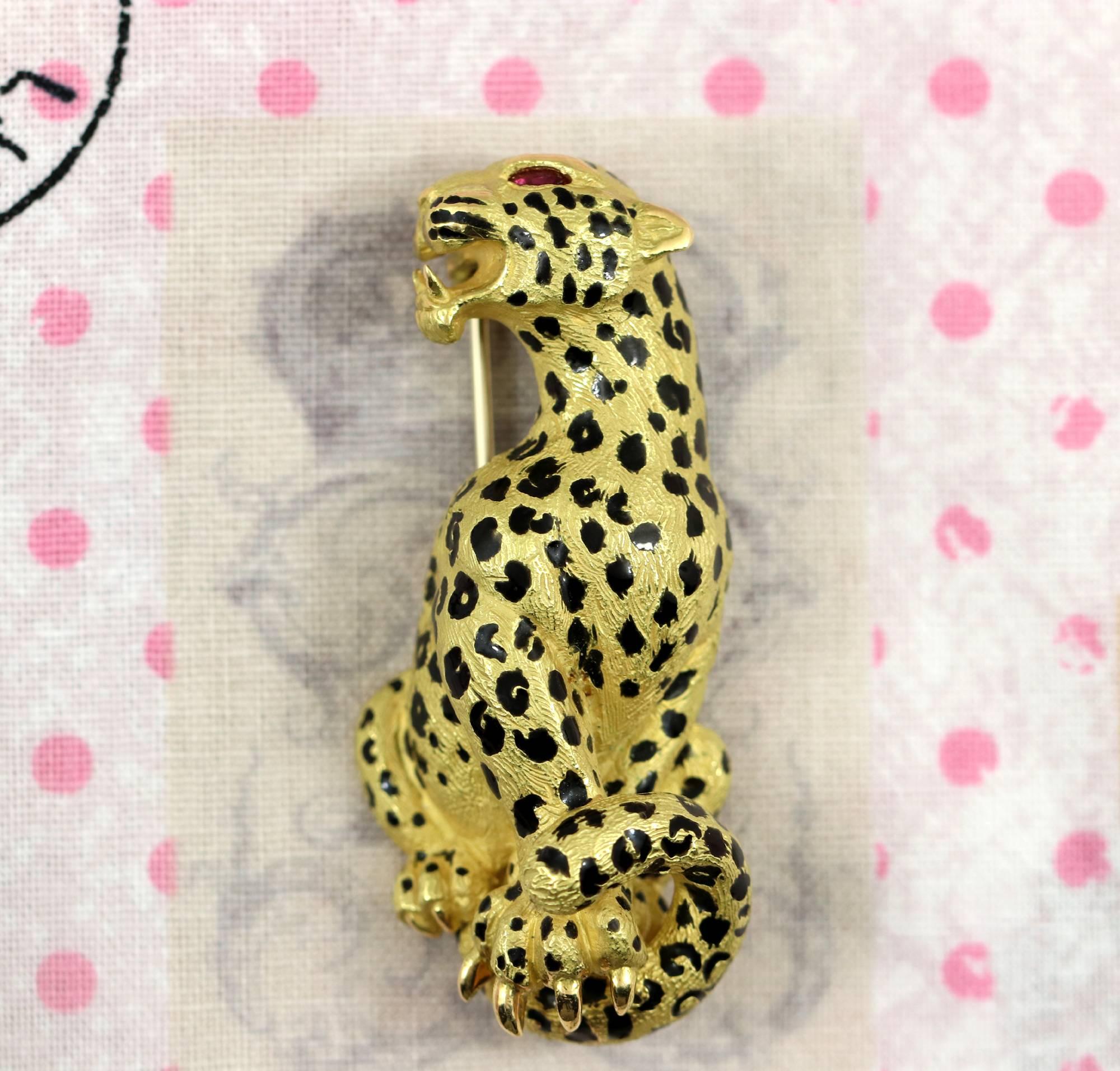 An 18K yellow gold brooch measuring 1 7/8 inches long, and 3/4 of an inch wide, detailed with black enamel, to give this big cat it's spots. With a ruby eye for drama, it is truly wild. Featuring French Hallmarks, it weighs 23.6 grams.