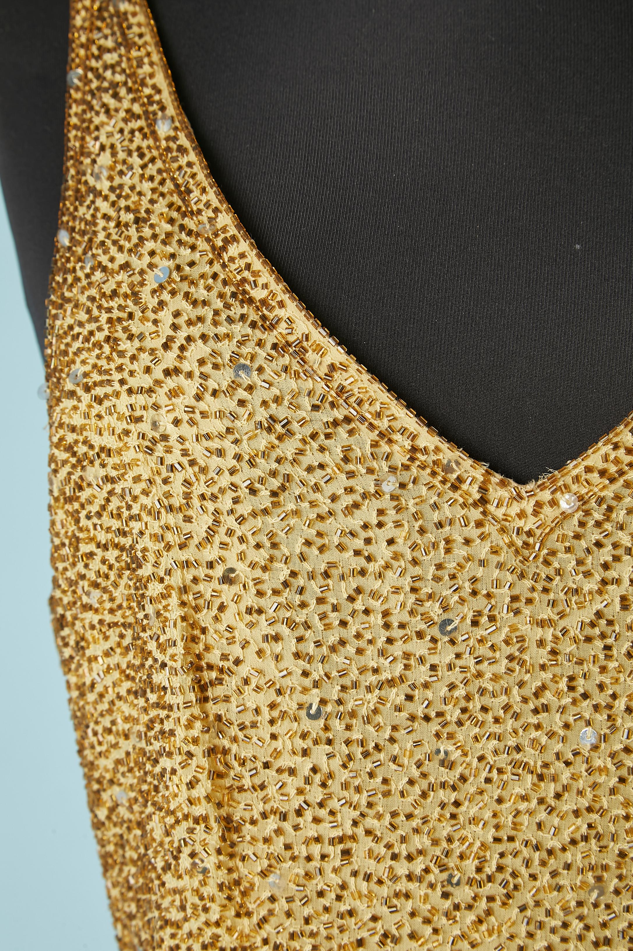 Gold full beaded ( glass beads ans sequins) evening dress entirely hand crafted. Main fabric : silk. Lining: polyester. 
Zip in the middle back and hook&eye. Extra beads provided. 
Split on the side front , lenght = 60 cm 
SIZE M 