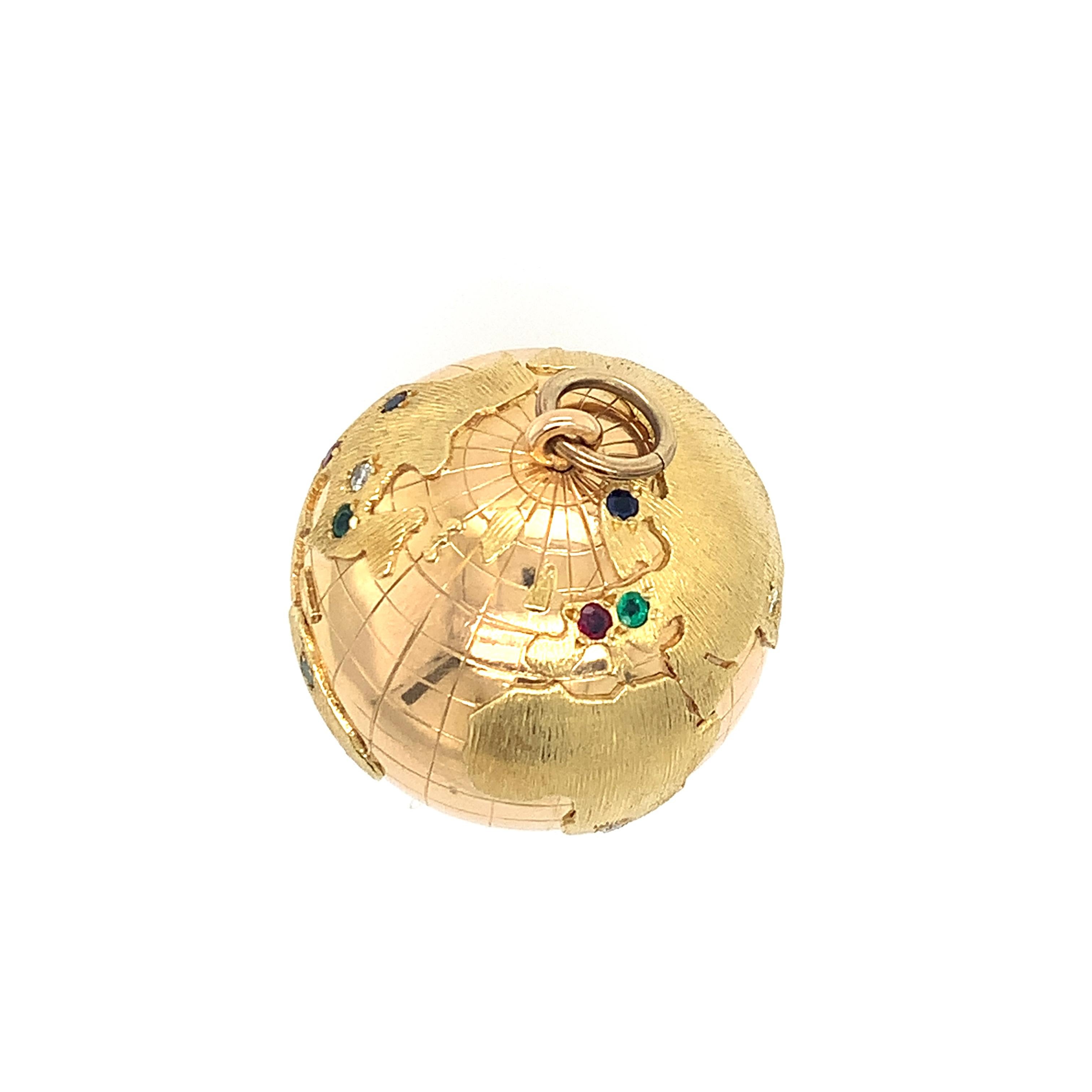 Large three-dimensional vintage 18K yellow gold dual finished globe charm set with sapphires, rubies, emeralds, and round brilliant cut diamonds. Featuring latitude longitude pattern with well-defined textured continents, this simple charm pendant