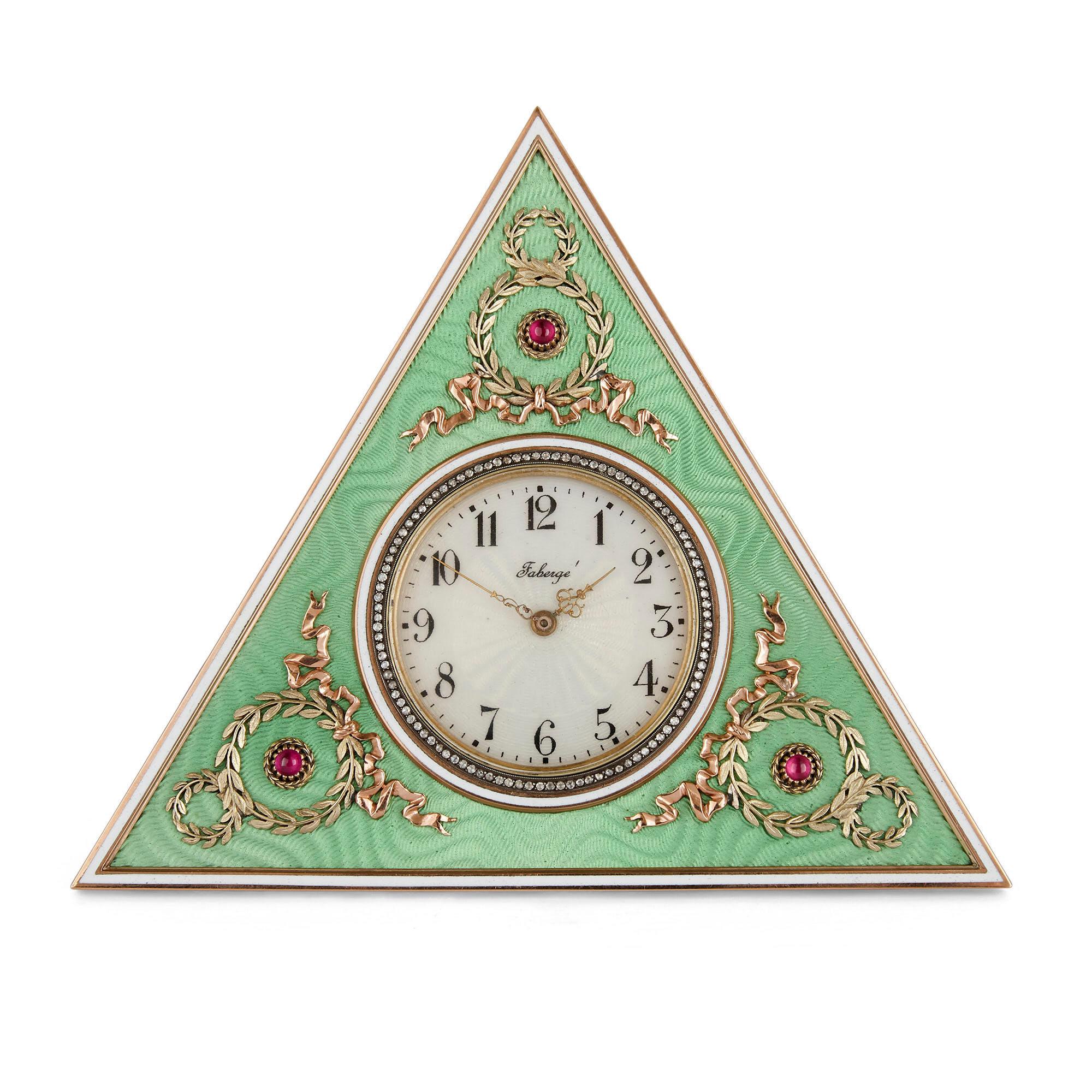 The surface of this triangular Fabergé style table clock is ornamented with green guilloché enamel, the exterior edge bounded by yellow gold inset with a strip of white enamel. The surface of the clock body is set at each corner with a yellow gold