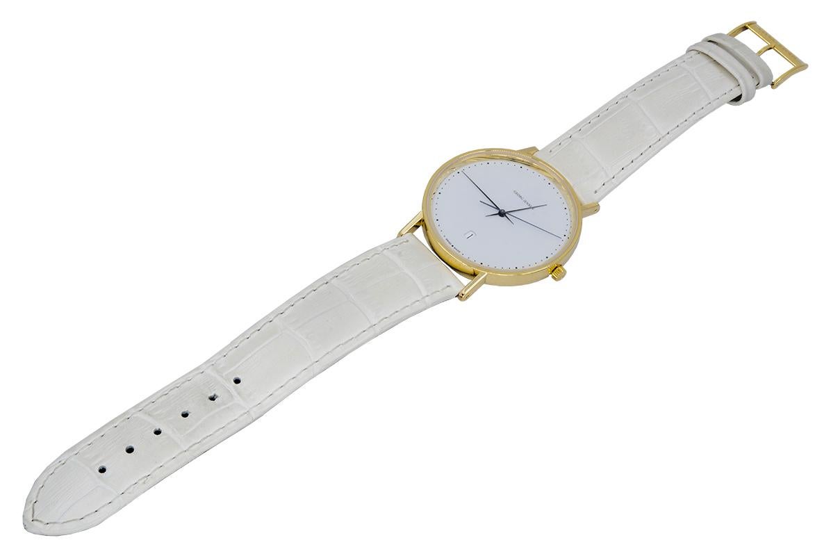 Large size wrist watch.  Made and signed by Georg Jensen.  Designed by Henning Koppel.  18K yellow gold watch and buckle.  Automatic.  Water resistant.  38mm.  Georg Jensen white leather band.  Made in Denmark with Swiss made movement.  A clean,