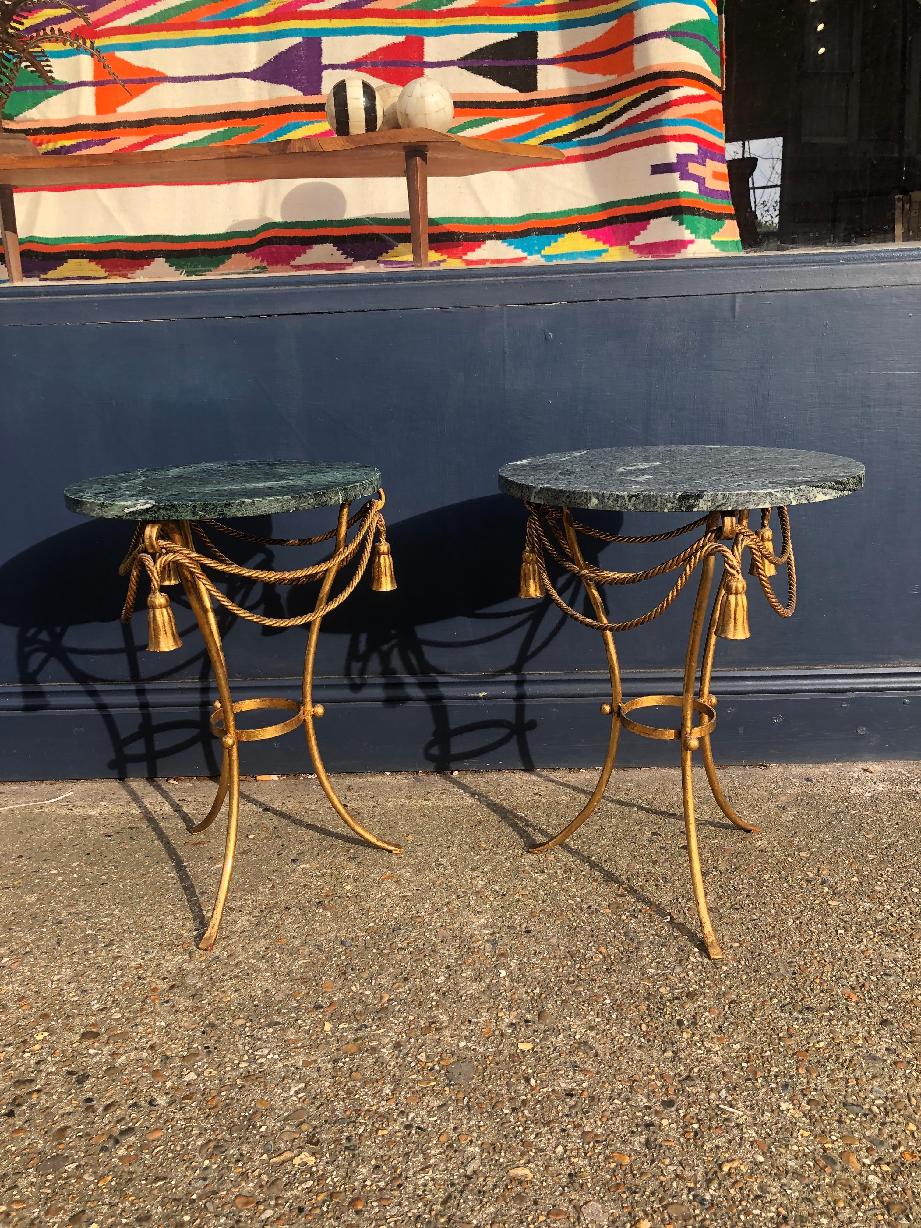 Un elegante tavolino con struttura in ferro con foglia dorata che rappresenta corde e nappe e che sostiene un piano rotondo in marmo verde. Un meraviglioso pezzo di design pratico che si adatta facilmente a qualsiasi interno, vintage o moderno.