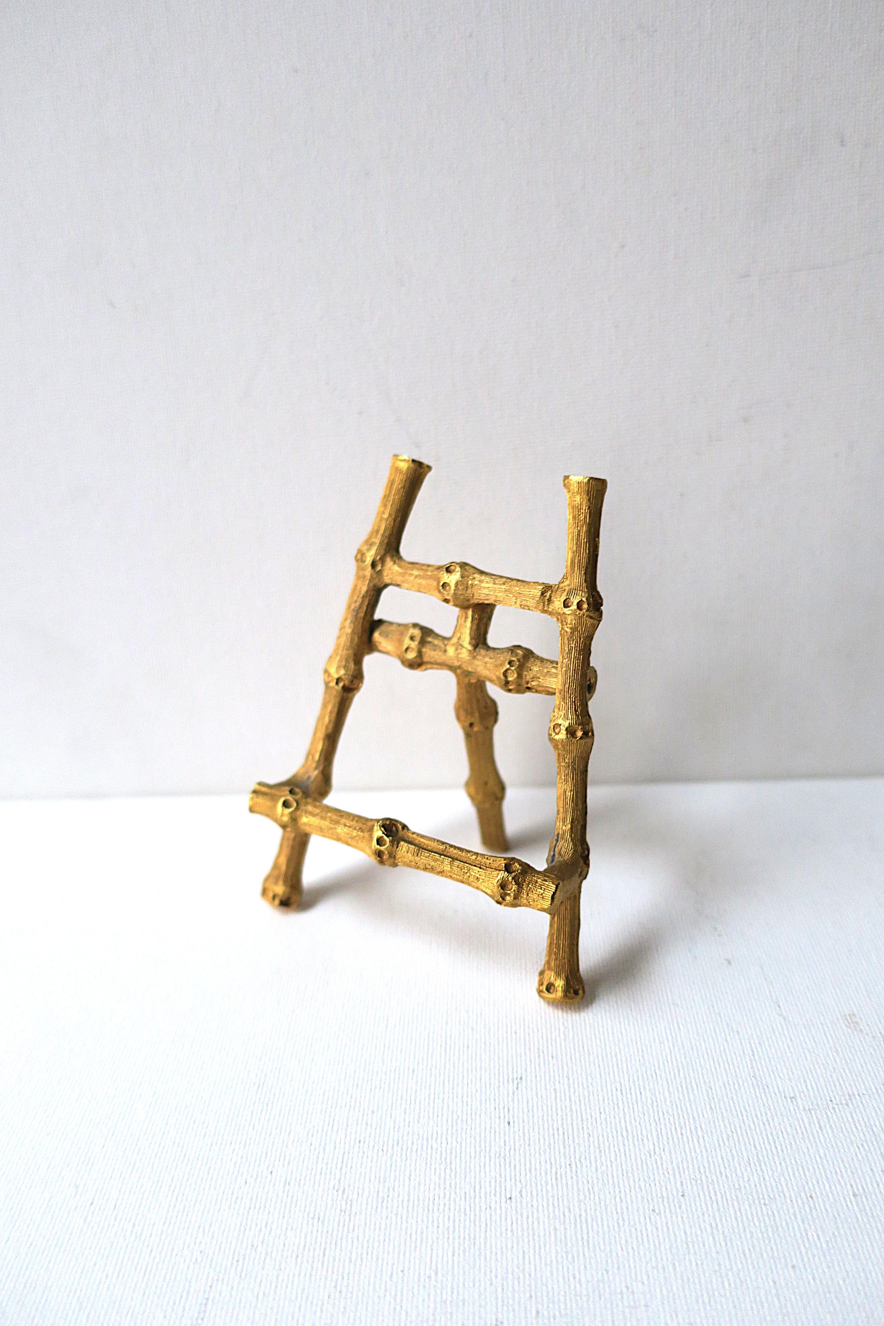 A small gold gilt 'bamboo' easel, circa 1960s. Piece is metal with a bamboo design and gold gilt overlay. A great piece to hold/display small items, art, signage, etc. Shown holding business cards and a post-card (5