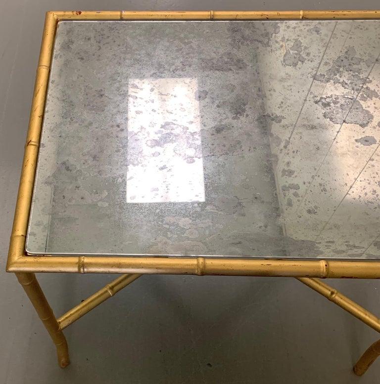 Gold bamboo style side table or end table. Metal faux bamboo table with hand painted gold gilt finish with red undertones. New antique style mirrored glass top.