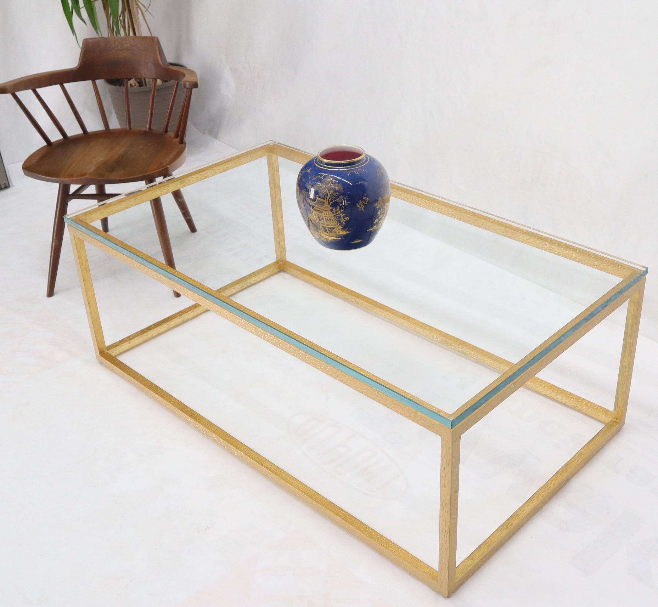 Table basse à plateau en verre épais et à structure lourde soudée, finition dorée.