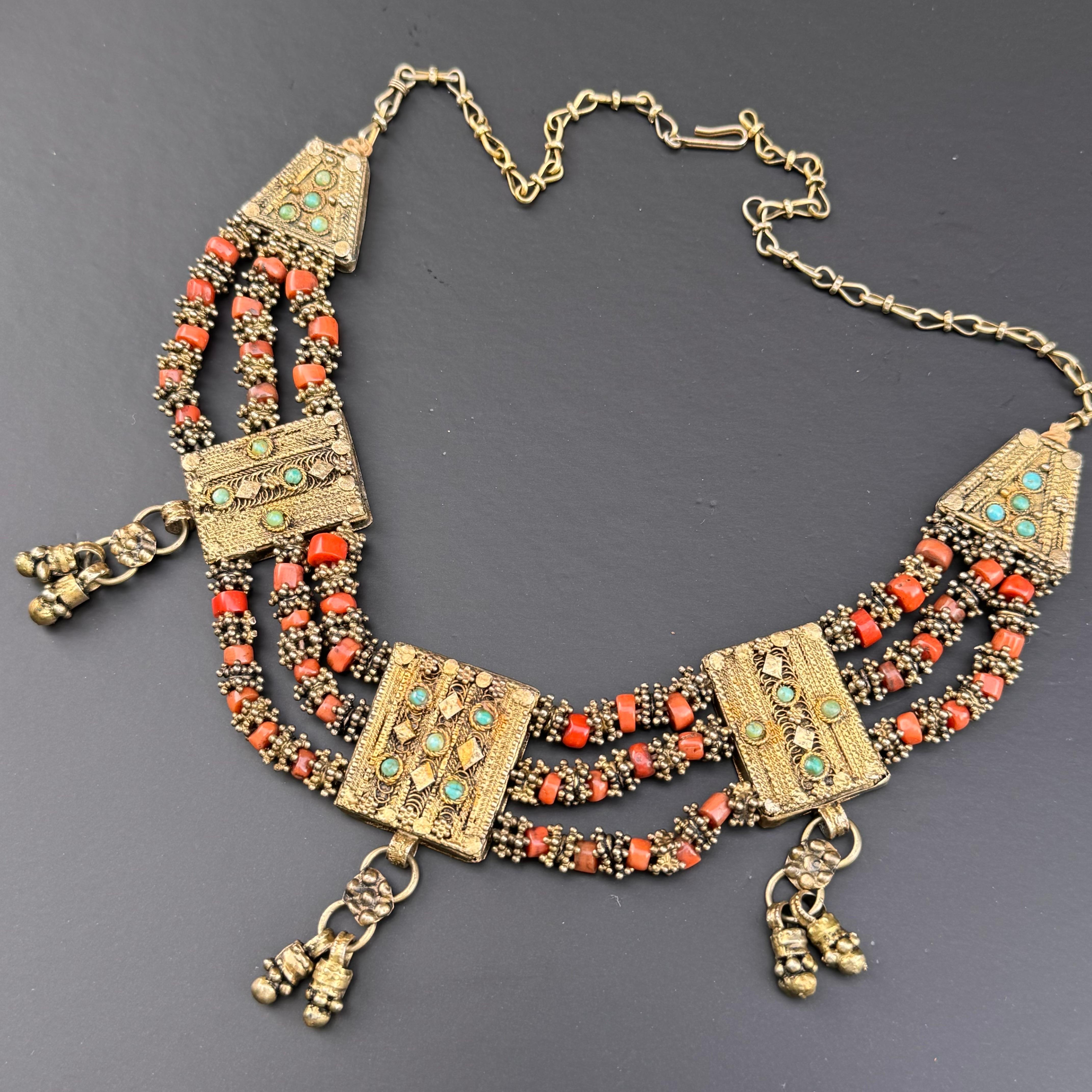  Vintage Yemeni Coral  Bib Necklace, meticulously handcrafted by skilled Yemeni Jewish silversmiths. Intricately designed with gold gilt silver, adorned with vibrant coral and turquoise gemstones in applied work panels. This necklace reflects the