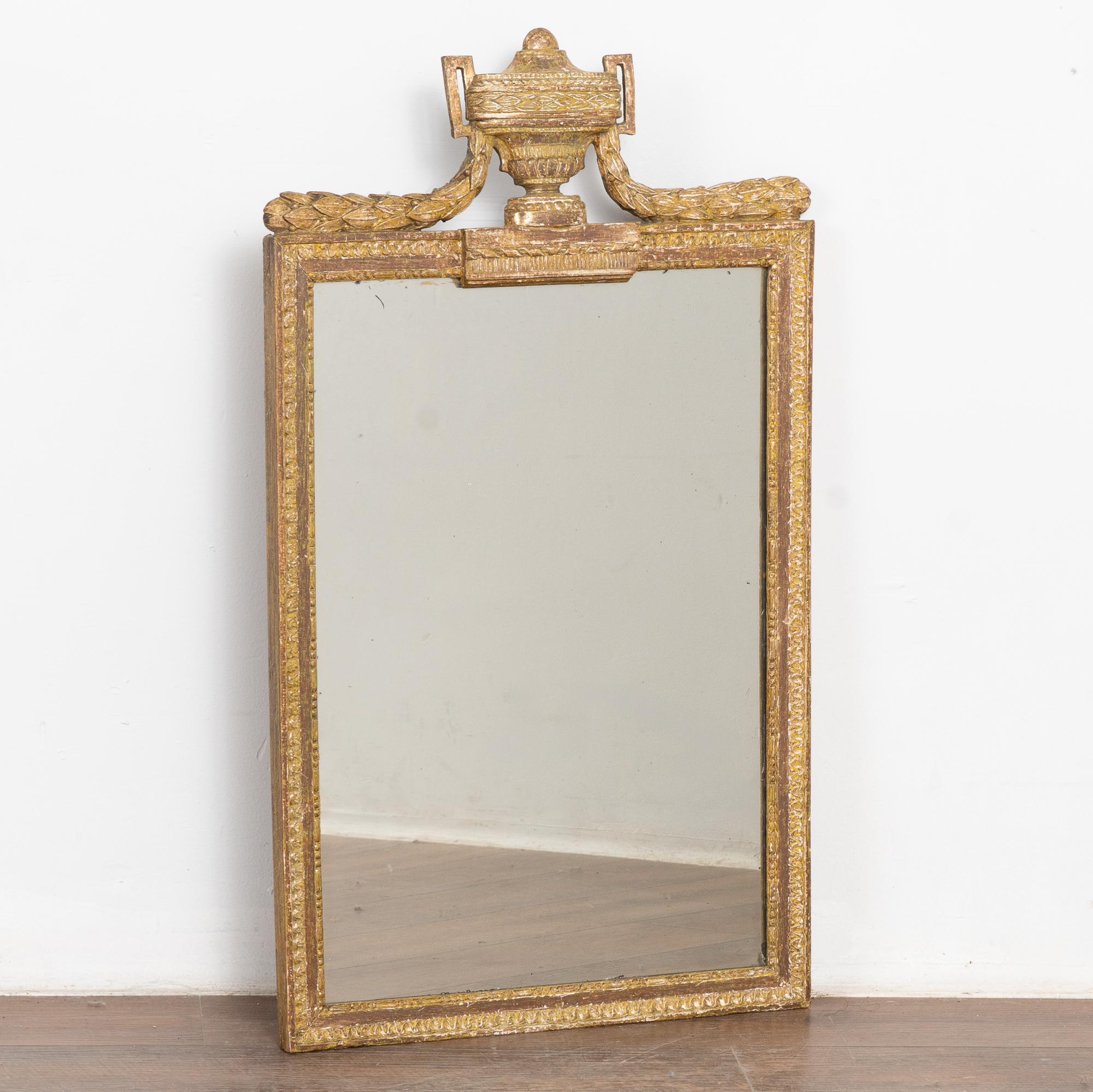 Ce miroir remarquable est couronné d'une urne et d'une guirlande grecques sculptées.
L'or bruni et le rouge/brun brique accentuent la beauté de la sculpture, avec de légères nuances de jaune/vert/blanc.
Il y a des traces d'usure dues à l'âge, comme
