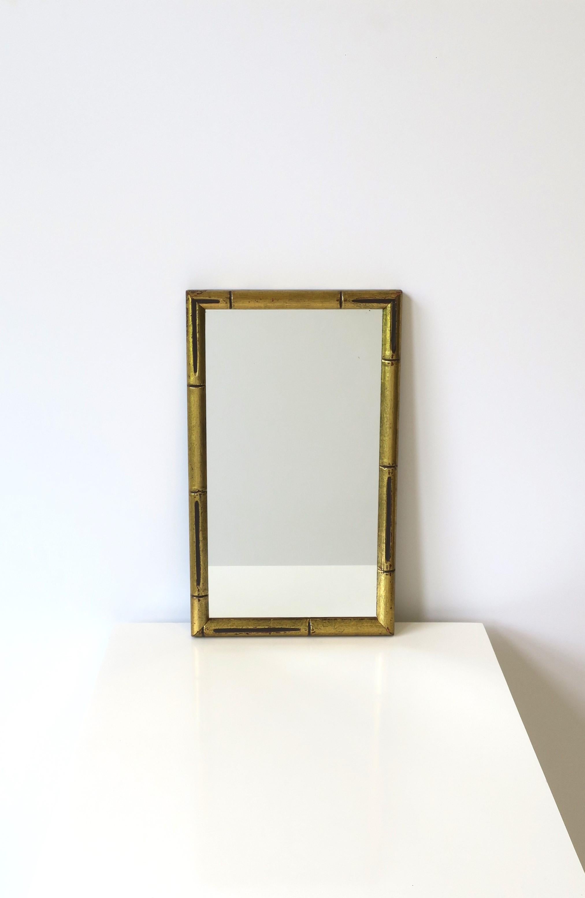 A gold giltwood bamboo style framed wall or vanity mirror in the Chinoiserie style, circa late-20th century, New York. Mirror is rectangular with a gold giltwood frame and design details that give it a 'bamboo' look. A great mirror for any wall