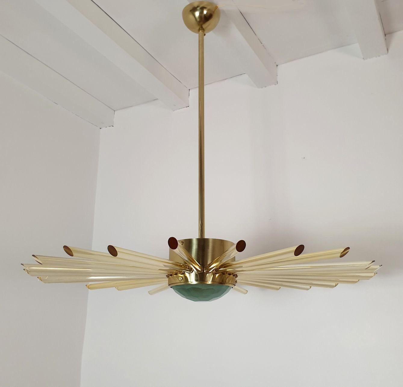 Large Mid Century Modern Sputnik chandelier, Italy 1980s.
The Mid Century Sputnik chandelier is made of a polished brass frame and golden yellow plain glass tubes.
The center bottom glass is pale green and translucent, nesting the light.
The vintage