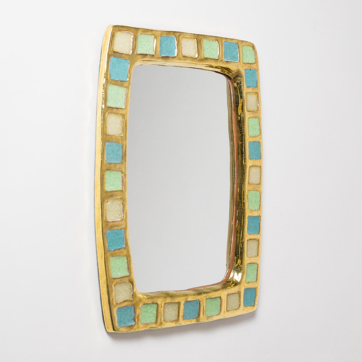 Lovely ceramic mirror by Mithé Espelt, one of the great French midcentury ceramic artists. Organic rectangular frame with gold glazing and muted pastel insets in three colors. Very fine original condition. Do to the glossy gold glazing on the
