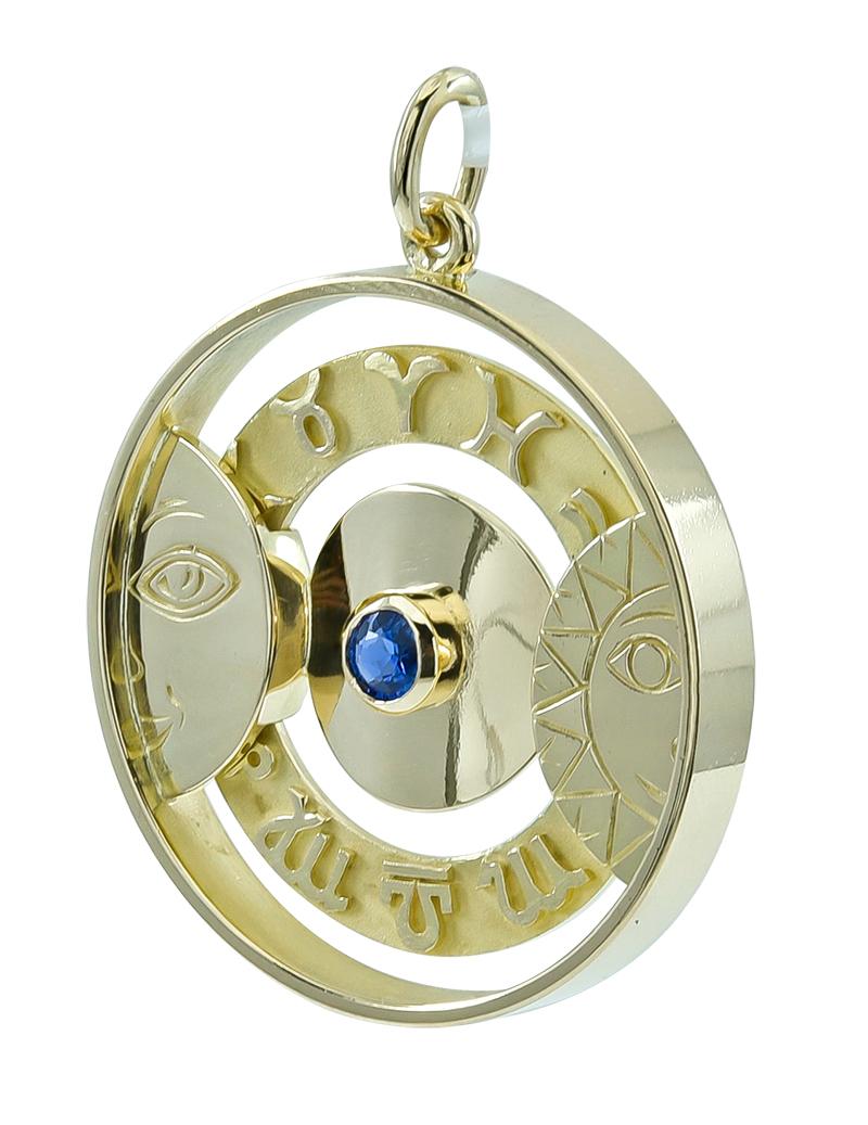 A unique charm:  a deep round disc,  made and signed by GUBELIN.  Rotating disc with applied symbols representing the astrological symbols.  A faceted sapphire is set in  the center.  On the left side is an applied figural moon face; on the right