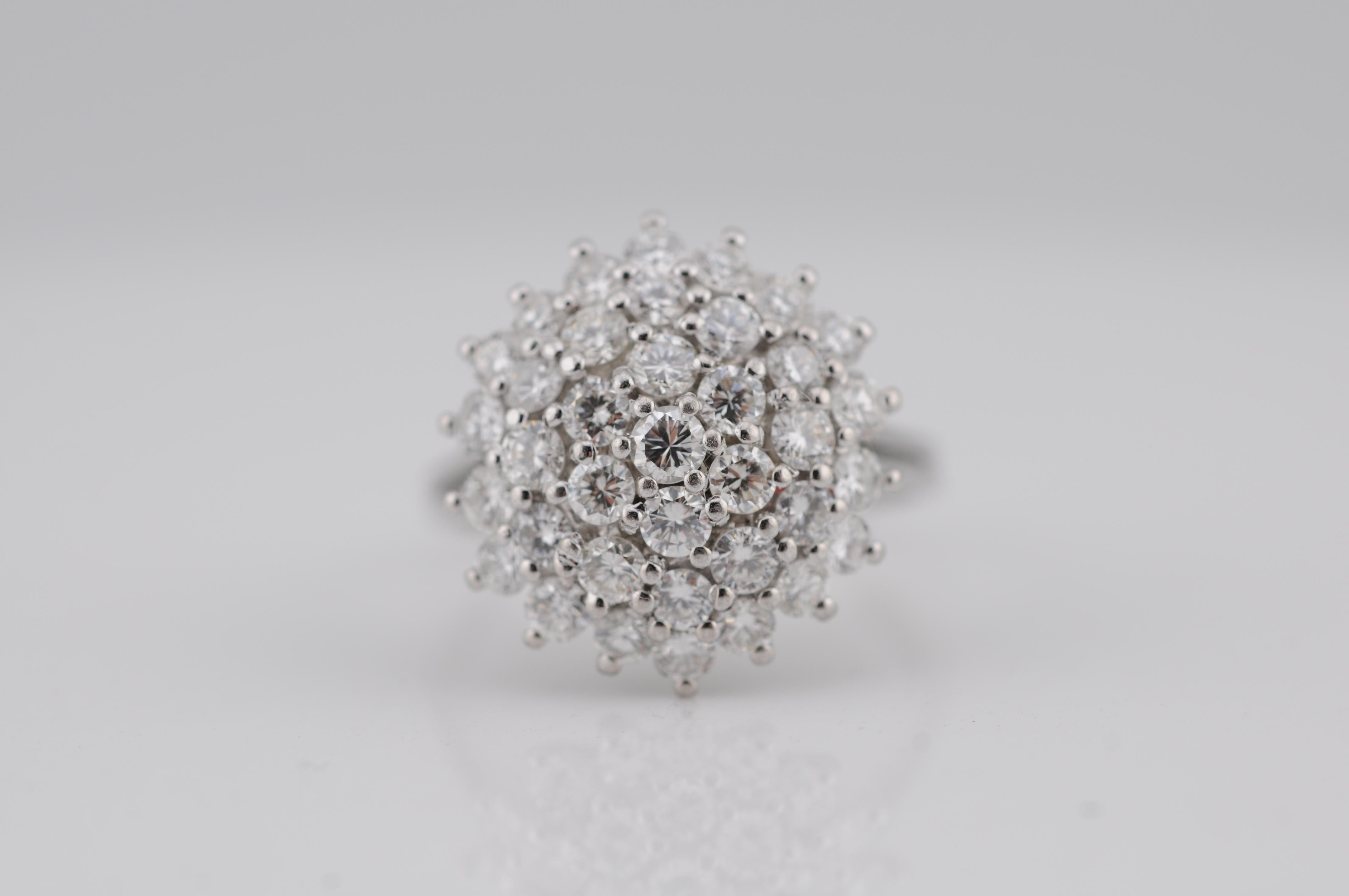 Anello aureolato con diamanti a grappolo realizzato in oro bianco 14k. L'anello è incastonato con diamanti a taglio brillante per un totale di circa 1,65 ct, con colore e purezza eccellenti. Un pezzo finemente realizzato con una presenza
