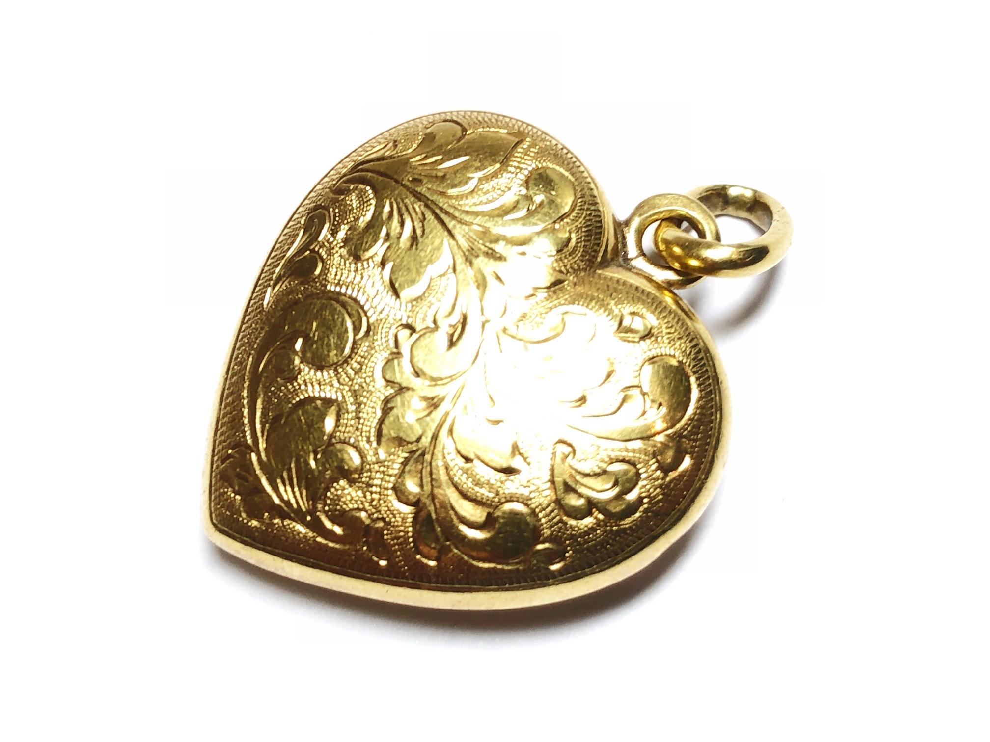 A heart pendant, with an engraved, foliage design, on the front, mounted in hollow, 14ct gold, made in Austria between 1922 and 1925.
