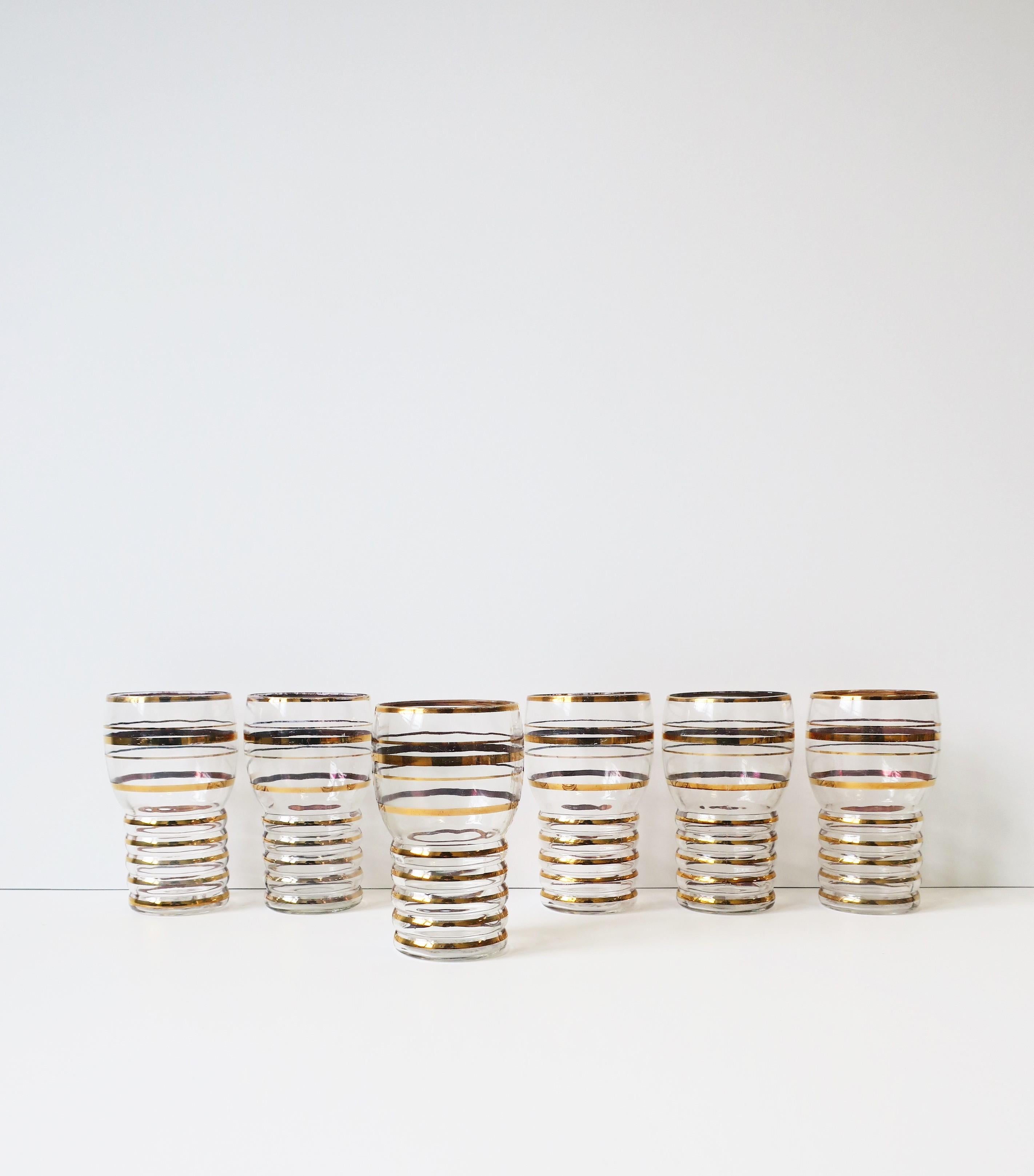 A shapely set of six (6) vintage/antique highball cocktail glasses with gold band design, circa early to mid-20th century. A great set for holiday or summer entertaining, and for any bar, bar cart, china cabinet, etc. Dimensions: 2.88