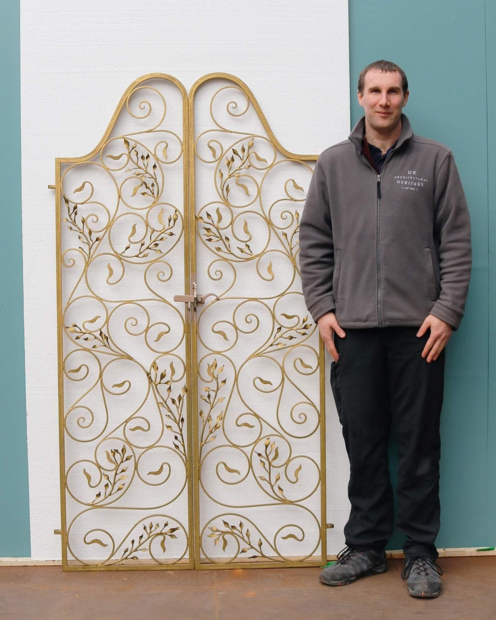 With their painted gold finish and ornate design, this set of Hollywood Regency style gates make a beautiful feature at the entrance to a garden or walled courtyard. Dating from the mid 20th century, these wrought iron gates are beautifully