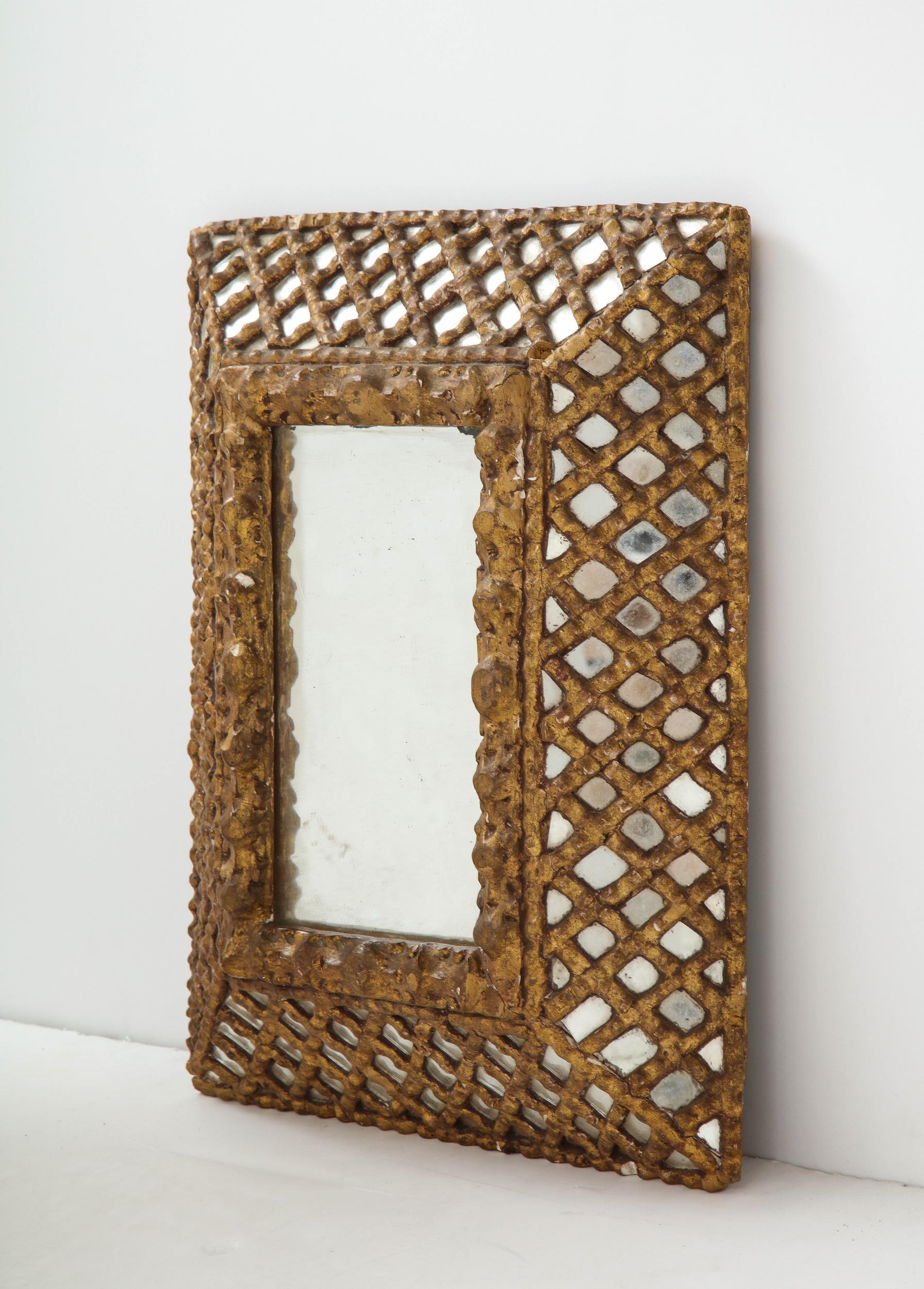 Miroir indien doré du début du 20e siècle. 

Miroir indien doré du début du 20e siècle avec des coins carrés et un cadre floral intérieur profondément sculpté. Le large cadre en treillis recouvre une bordure en miroir créant un motif complexe en