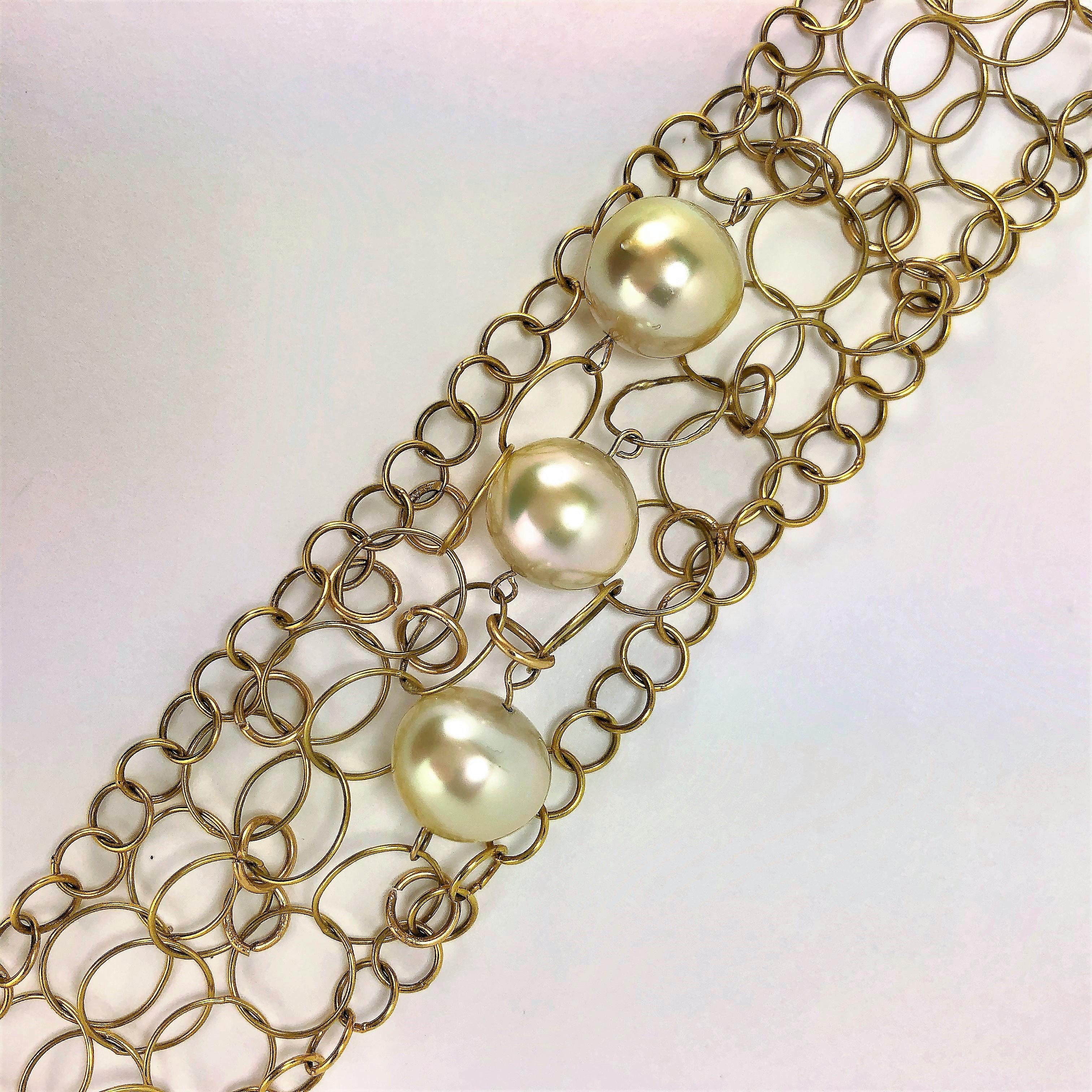 This delicate, stylish bracelet is fashioned from 14K Yellow Gold 
interlocking wire circles with three 12mm pearls featured in a diagonal 
line at the center. The unique push clasp is stamped 18K while the
intricate end pieces are stamped 14k.