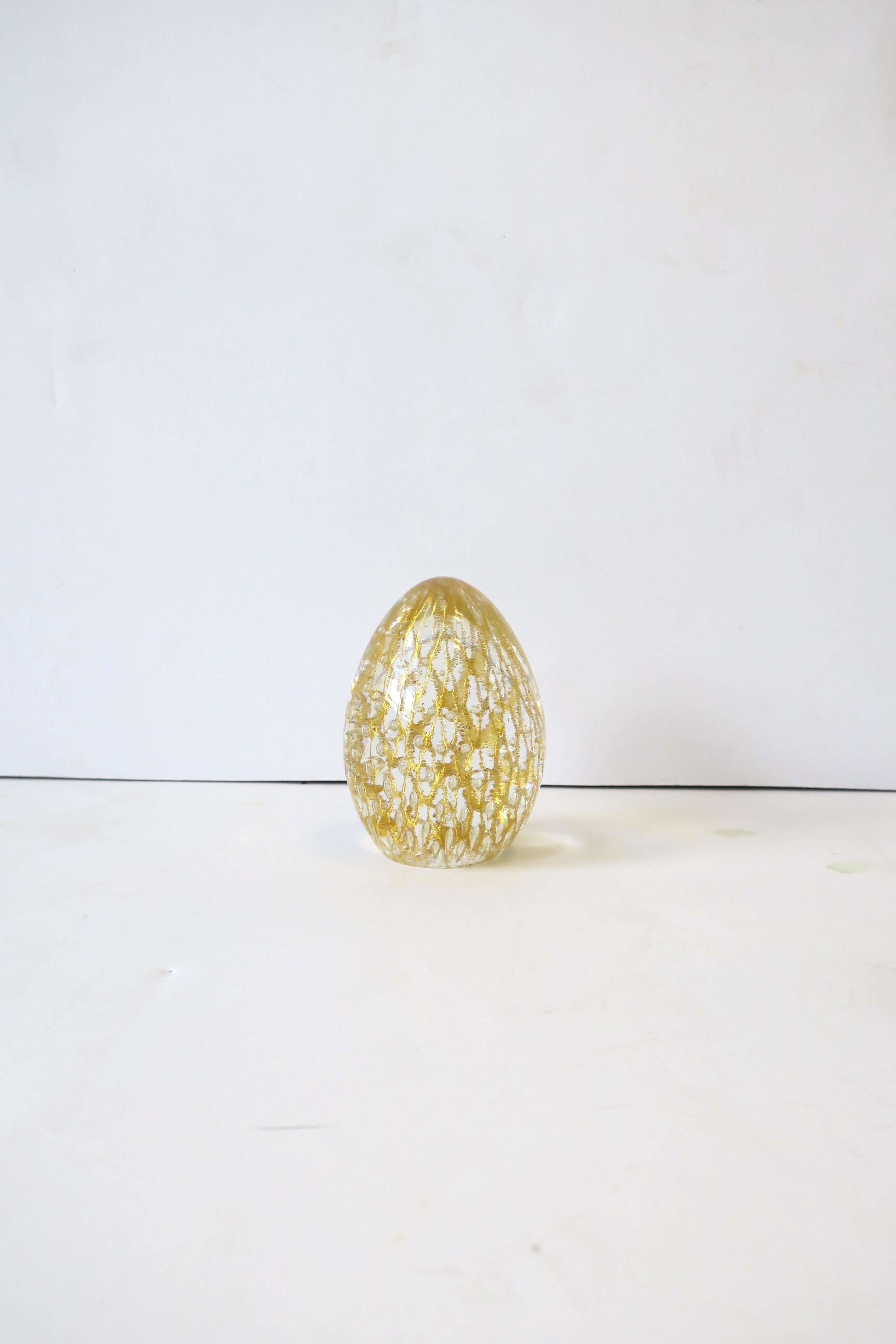 A beautiful Italian Murano gold and clear egg-shaped art glass object, circa late-20th century, Italy. This hand-crafted piece is shimmering gold and transparent Murano art glass. A beautiful decorative object (as demonstrated.) Marked 'Veniza'