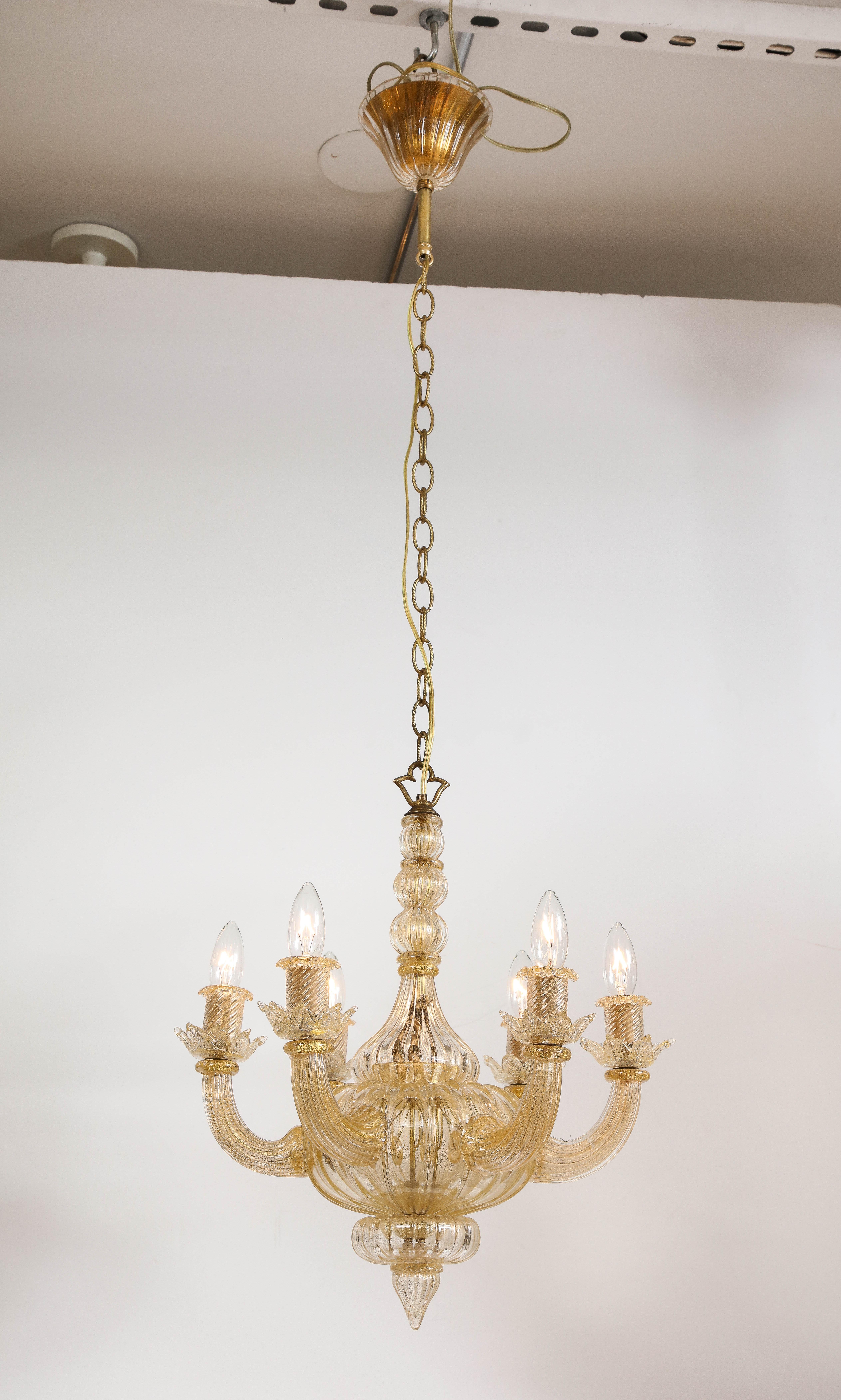 A midcentury hand blown Murano chandelier in semi-opaque hand blown Murano gold glass in an elegant neo-classical design with six curved upward arms ending with glass candle holders radiating from a fluted bulbous body, newly wired for the U.S.