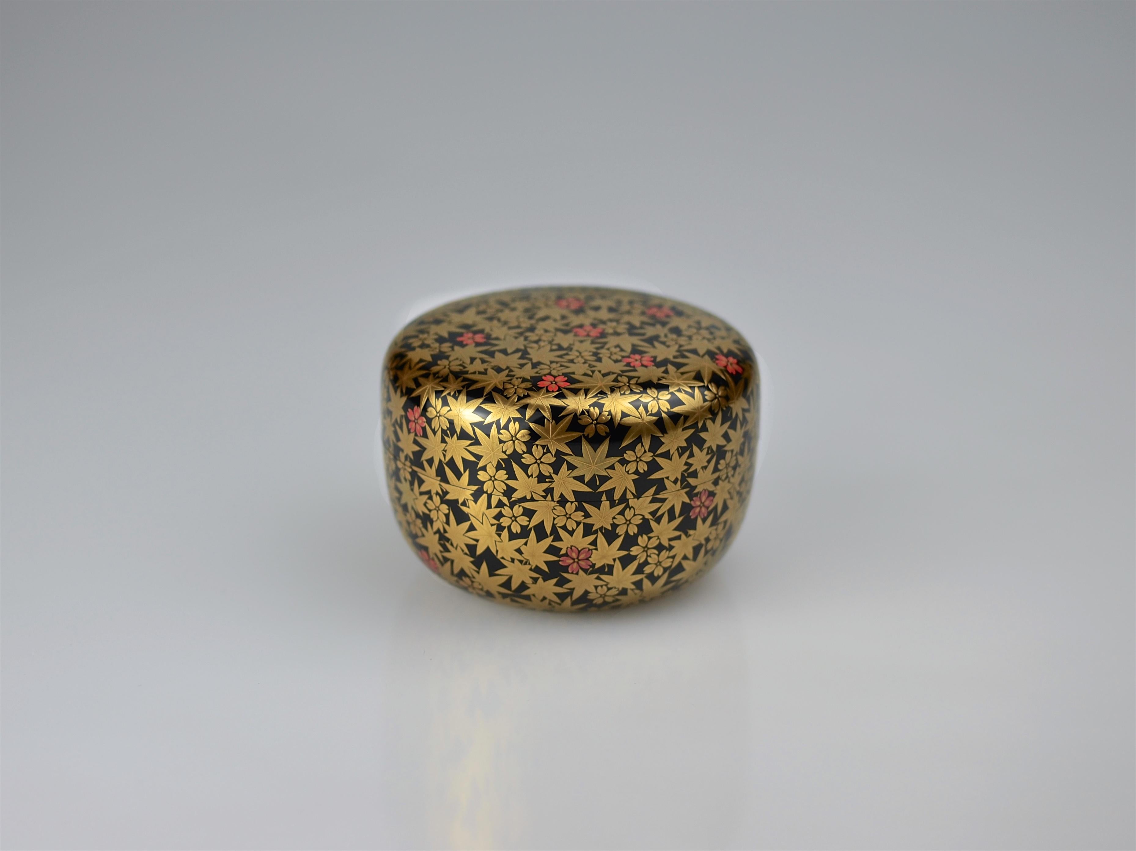 Excellent tea caddy (natsume) made by the 7th Ippyosai, Ippyo Eizo (1942). The exterior is finished in polished jet black lacquer (roiro) and decorated in gold maki-e with an all-over pattern over maple leaves and cherry blossoms. The cherry